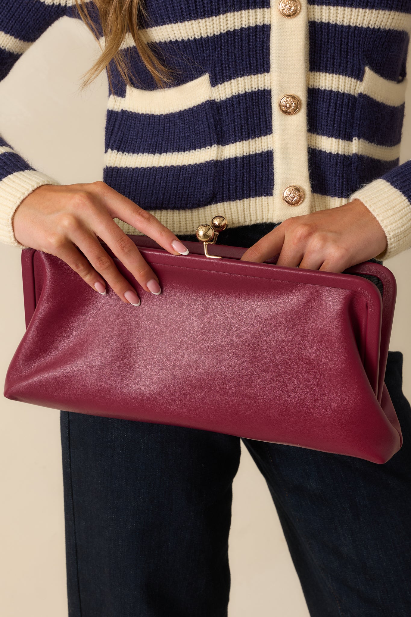 Close crop highlighting the structured frame and rich burgundy faux leather texture of clutch.