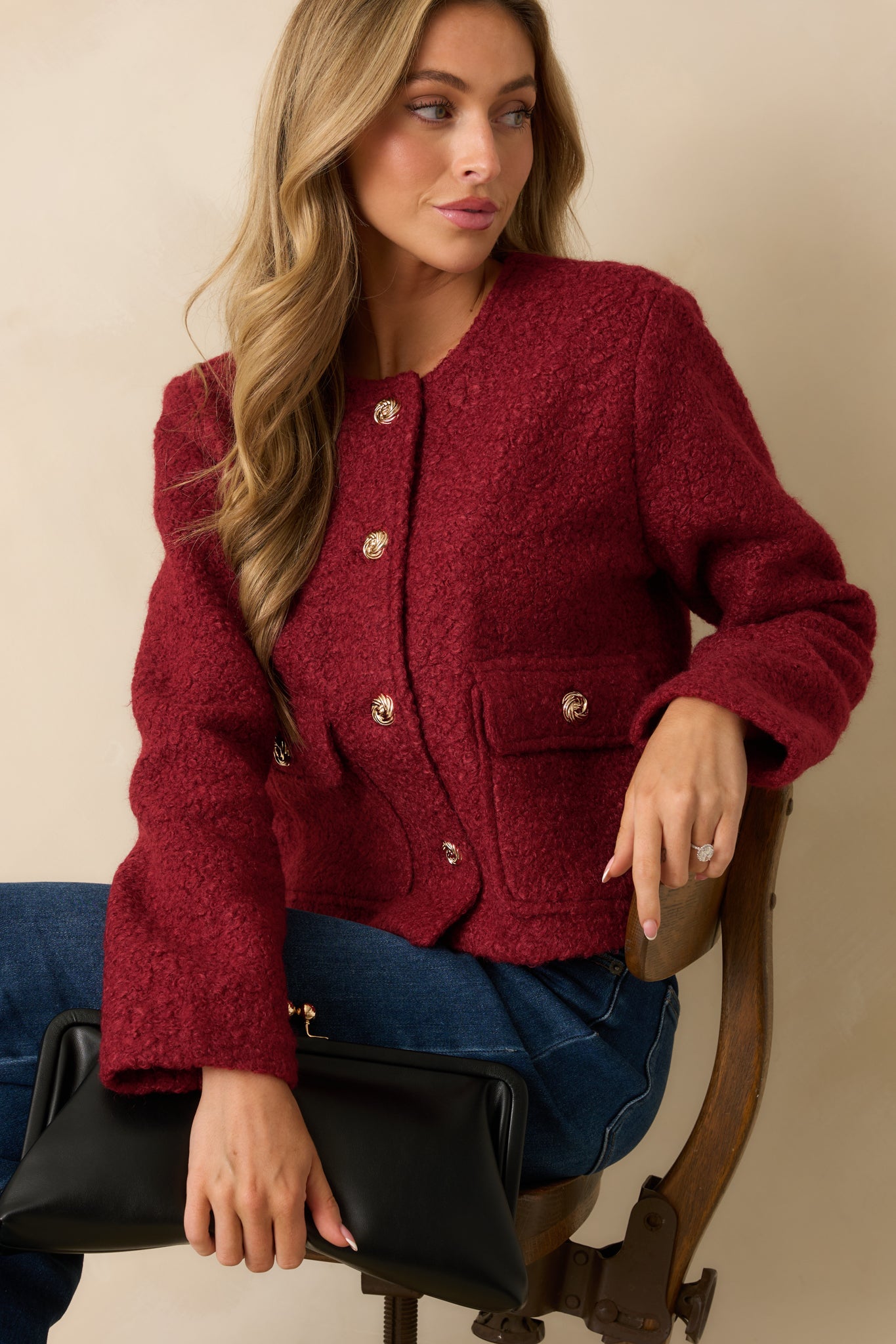 Crop highlighting the round neckline and rich bouclé texture of the cherry red jacket.