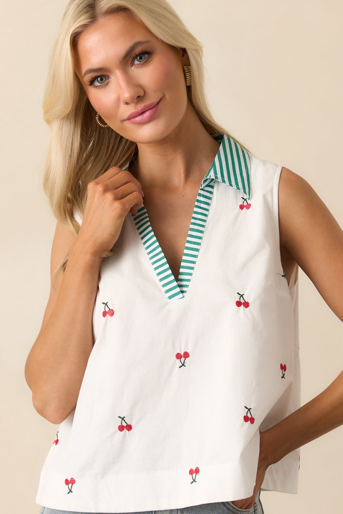 A close crop showing the sleeveless armhole cut and shoulder seam with cherry embroidery continuing around the edge.