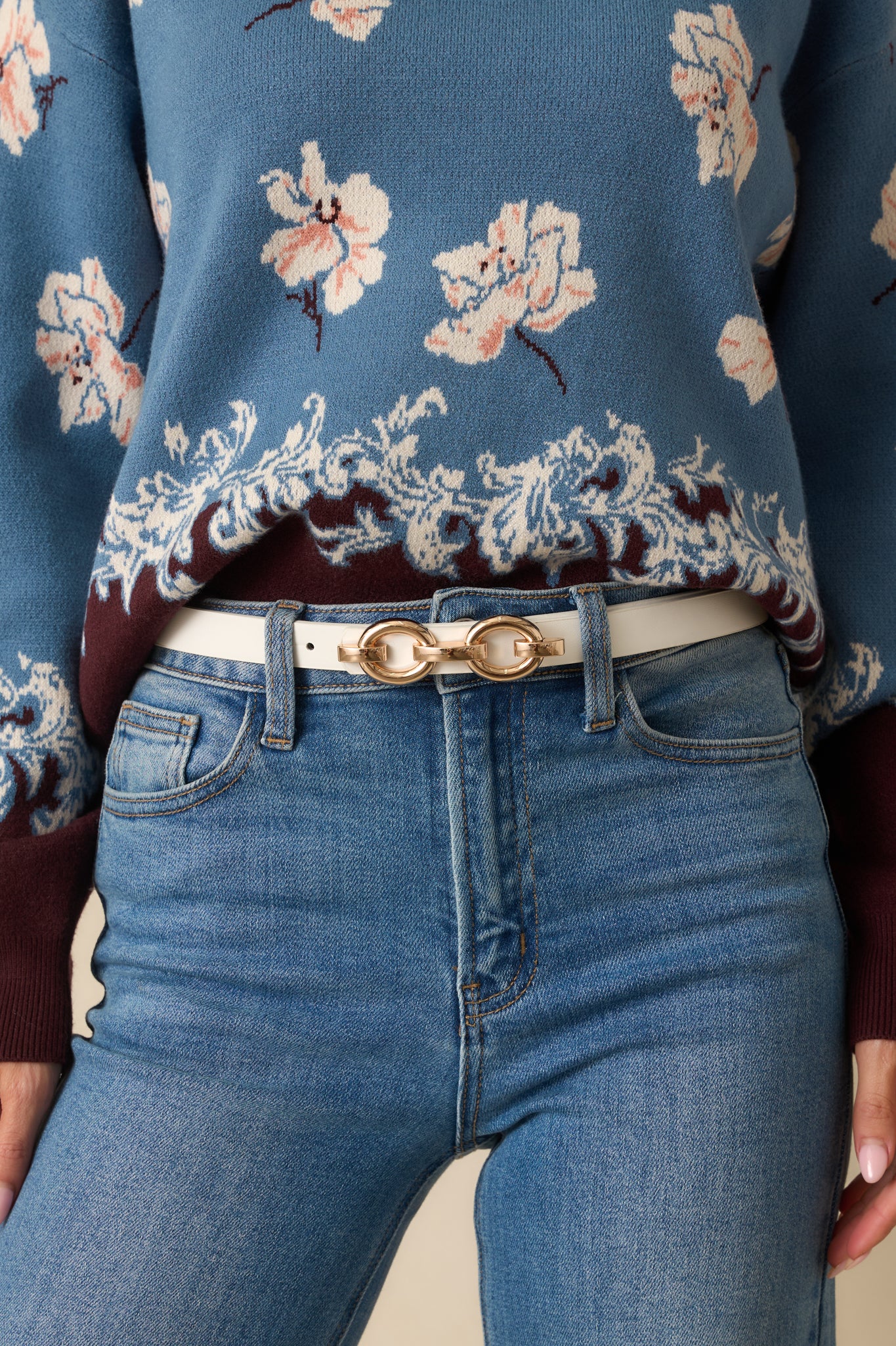 Cropped photo showing the white faux leather belt with a gold chain link buckle.