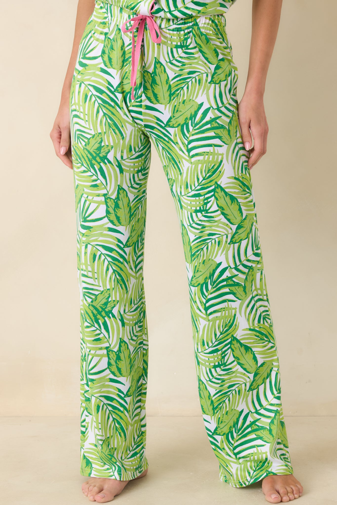 Close cropped angle of green leaf print pants showing relaxed fabric drape and soft lightweight material