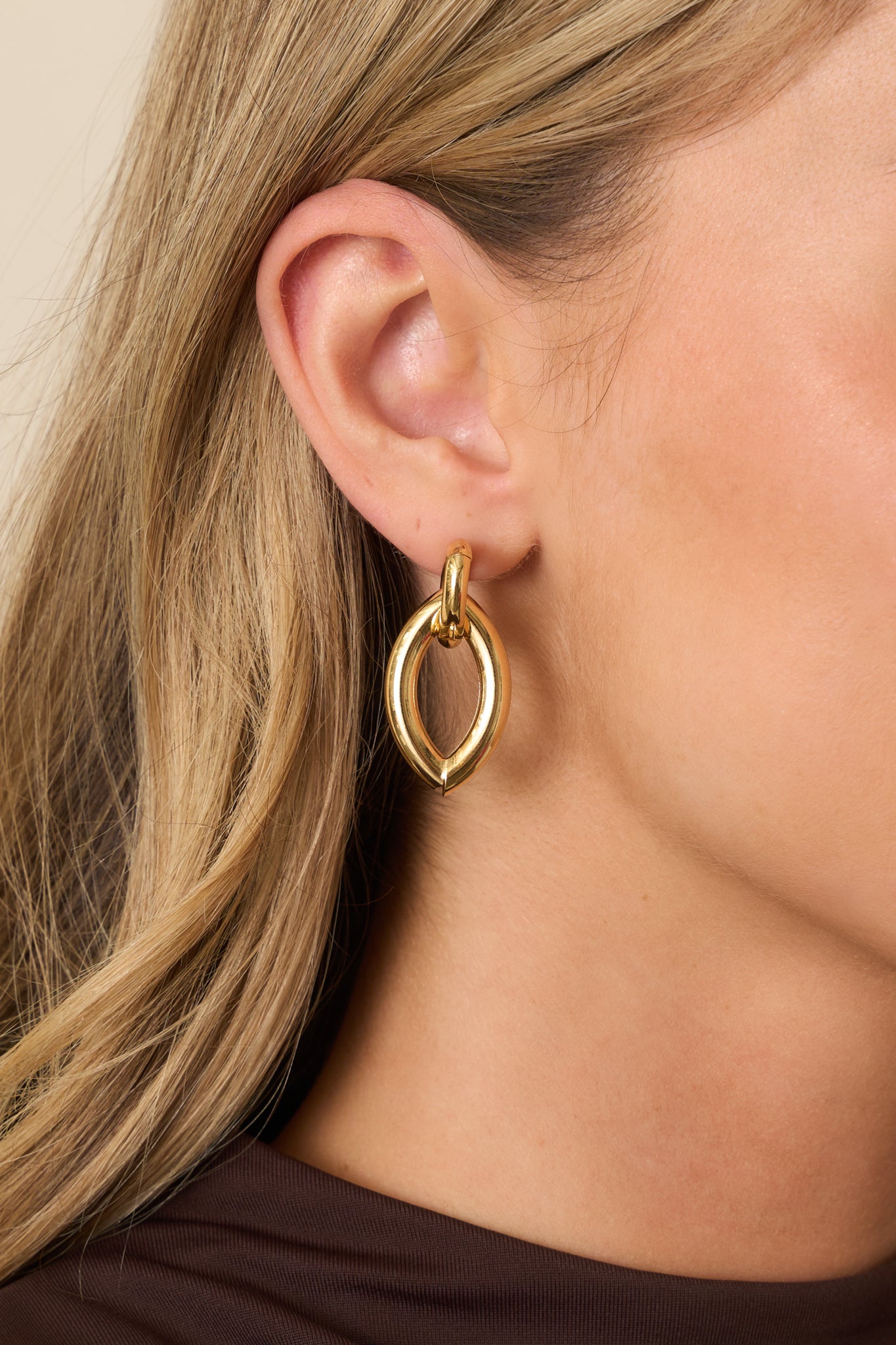 Cropped close view focusing on the sleek, curved shape and reflective gold-tone surface of the earrings.