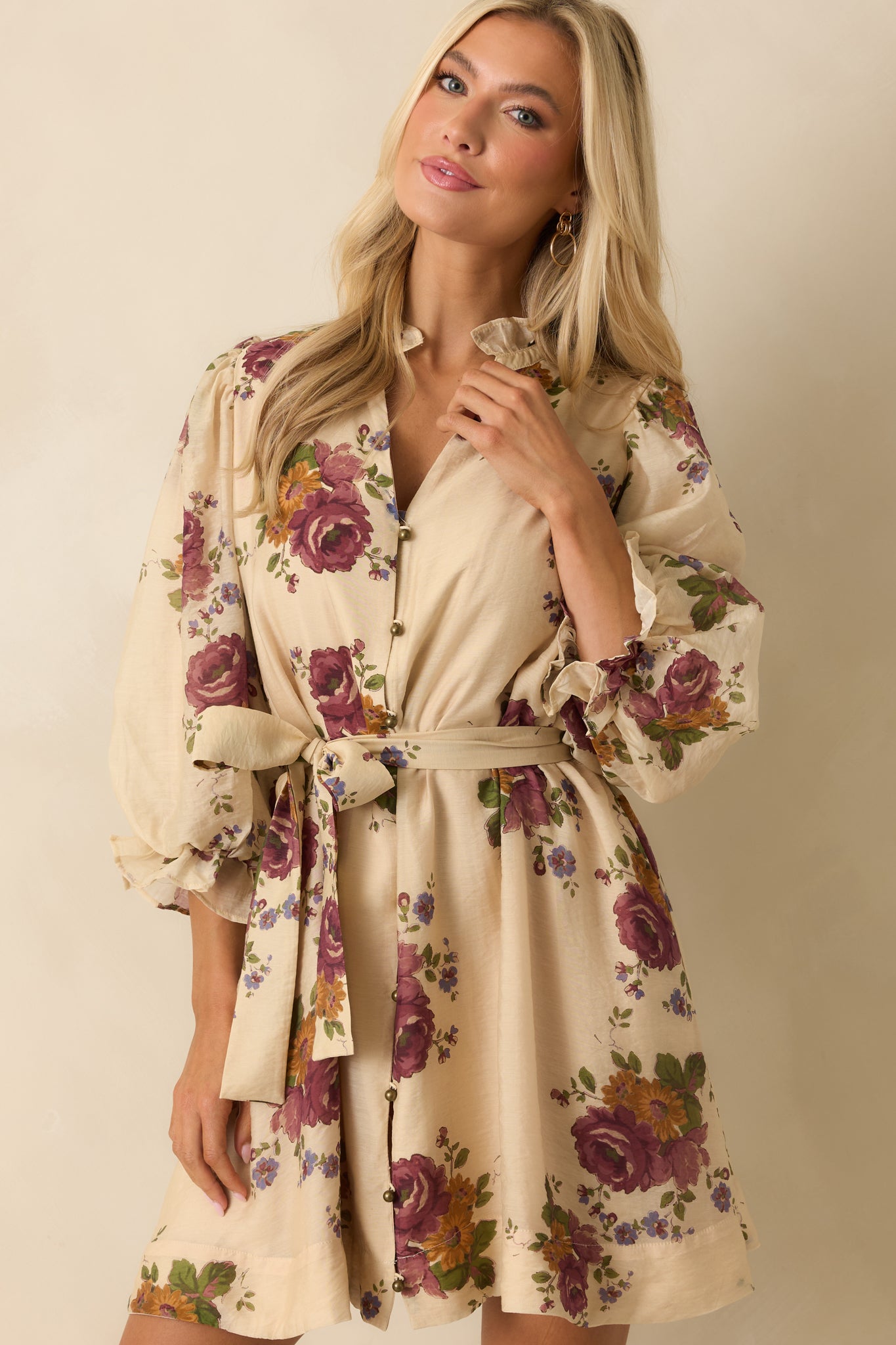 Cropped detail highlighting the side pocket and fabric texture of the beige floral mini dress.