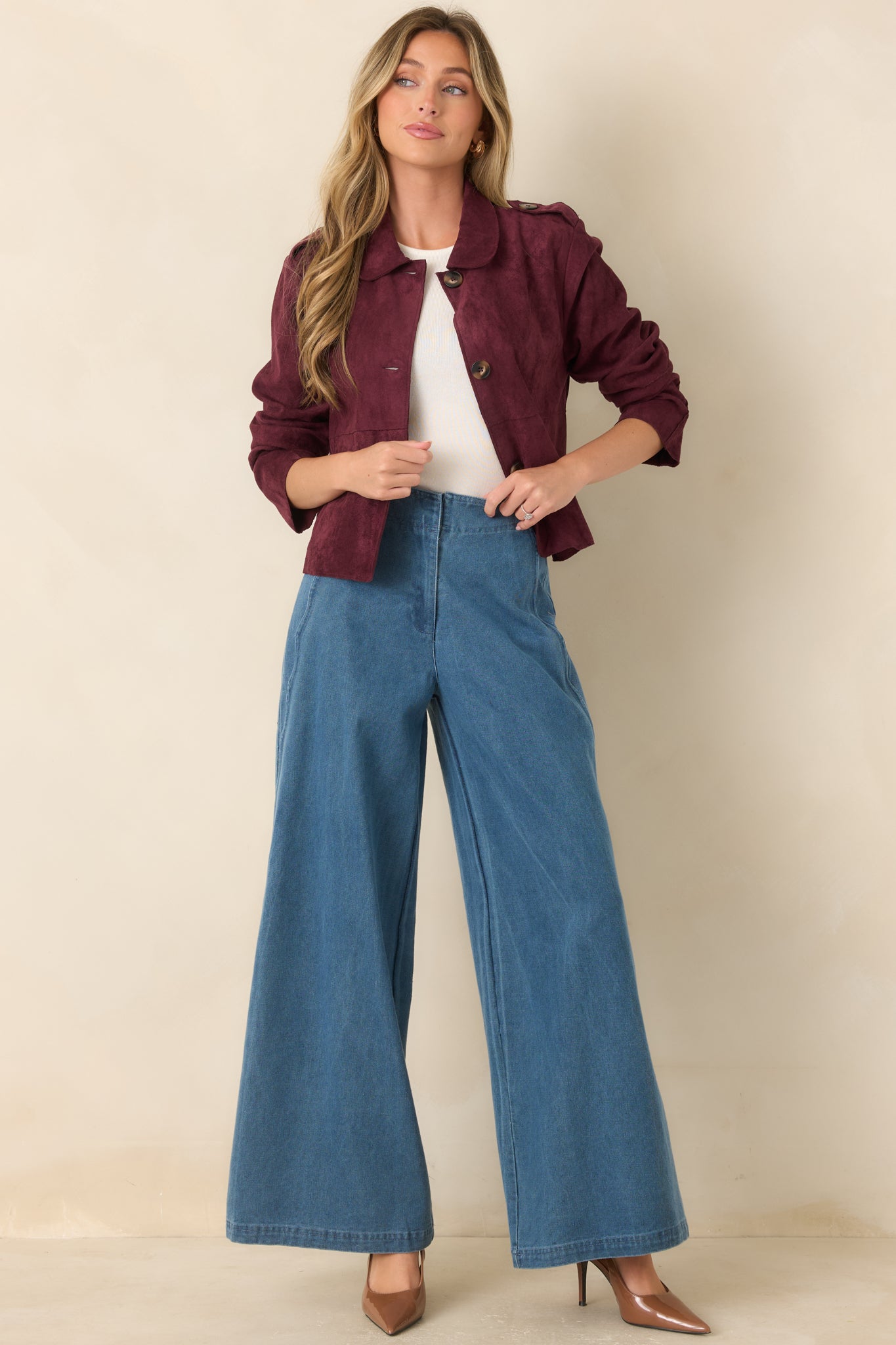 Cropped faux suede jacket designed with a rounded collar, button-front closure, structured patch pockets, and subtle shoulder tabs for refined everyday style.