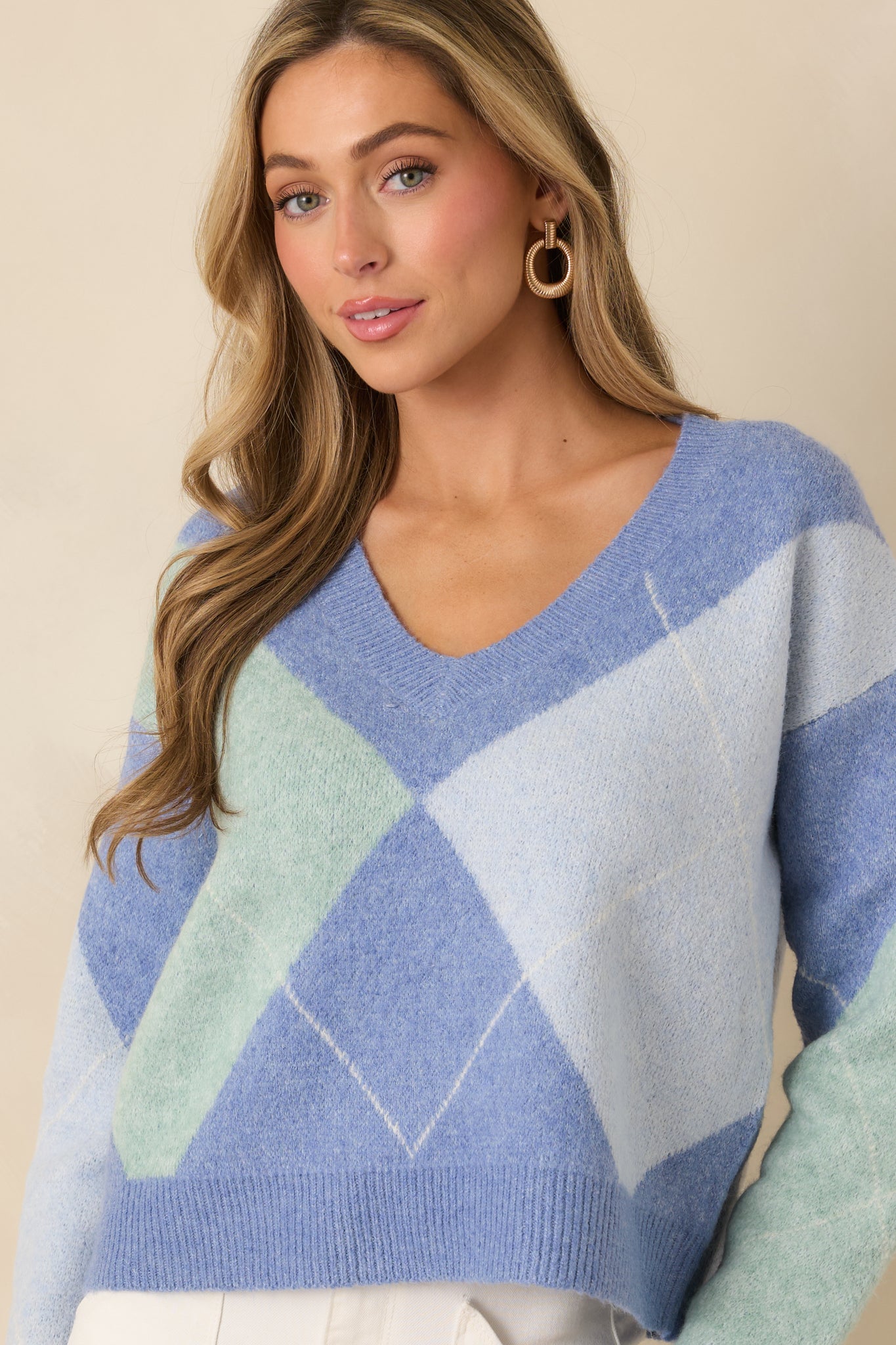 Cropped front view of the sweater focusing on the blue and green argyle pattern.
