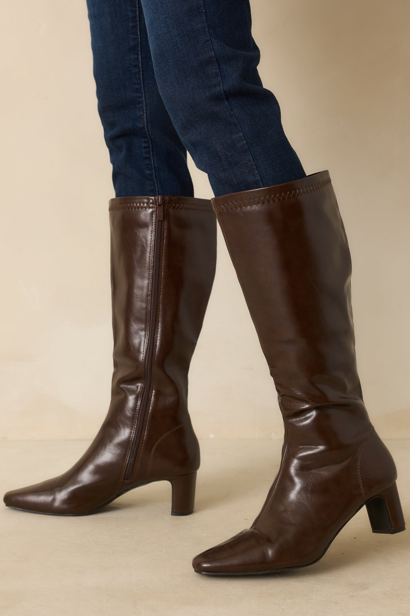 A cropped front view of the chocolate brown faux leather boots with a pointed toe and block heel.