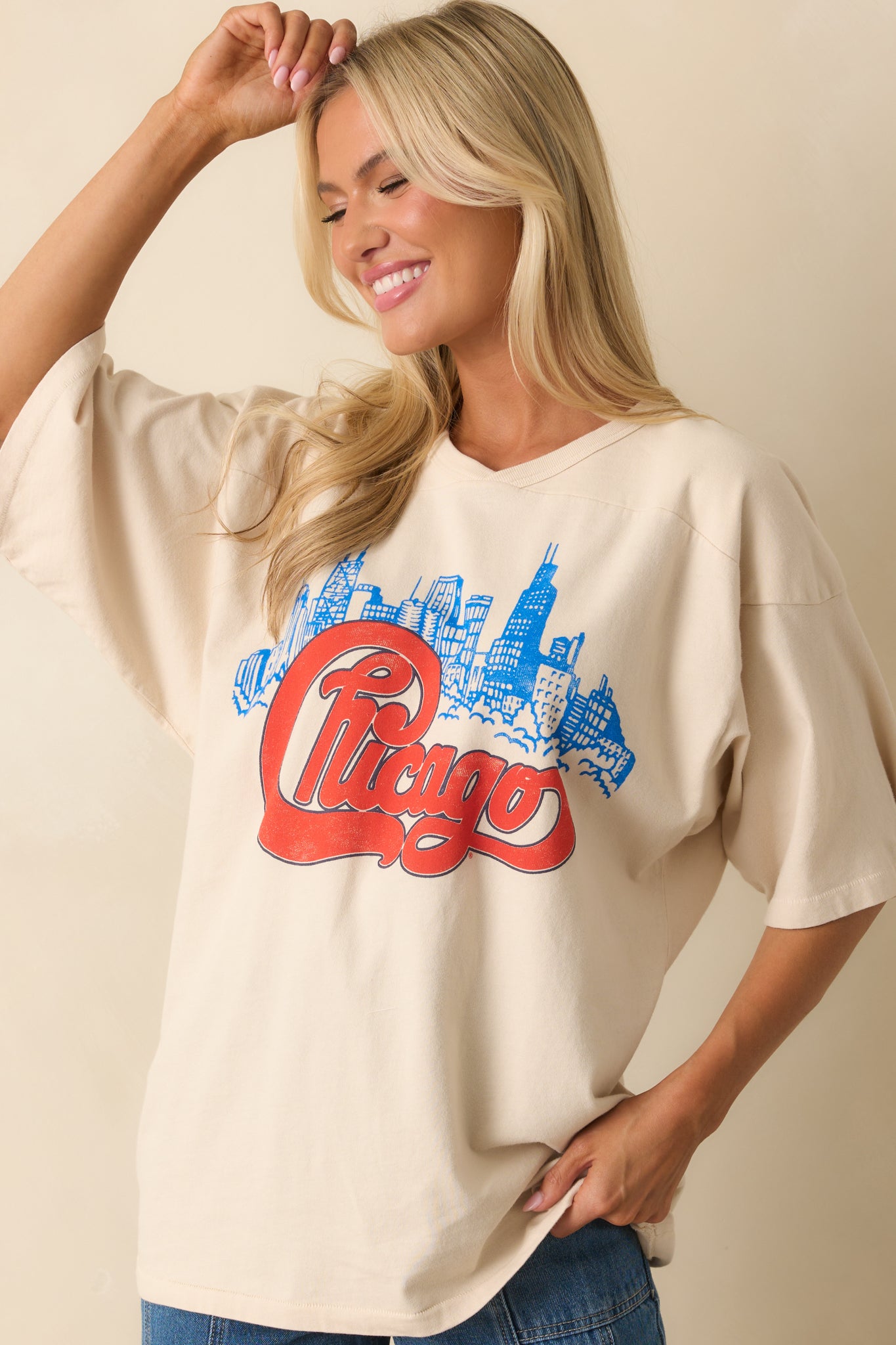 Cropped front shot of graphic ivory T-shirt showing skyline details beneath red “Chicago” lettering.
