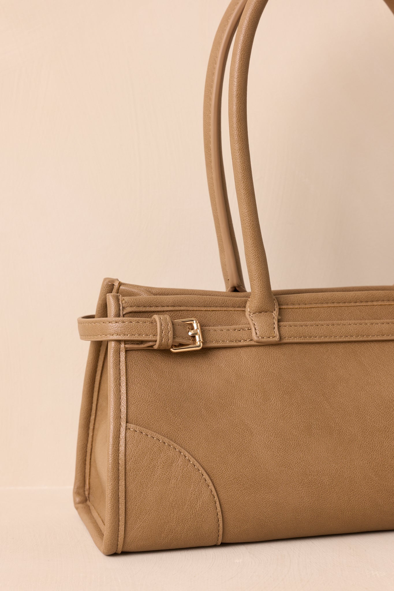 Cropped front view focusing on the top zip closure, belted side details, and handle attachment.