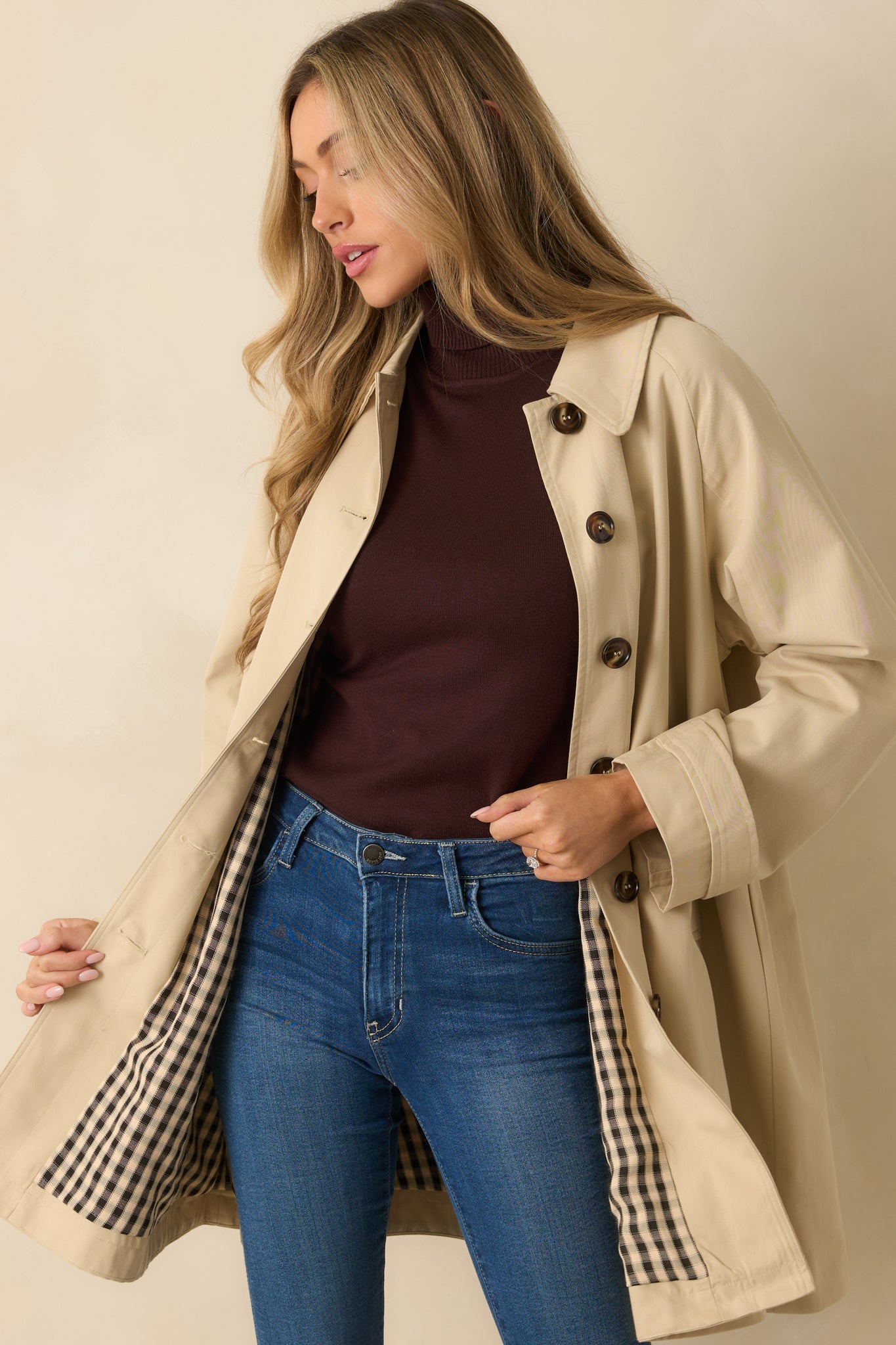 Cropped front view showing collar, buttoned cuffs, and front closure of beige trench jacket.