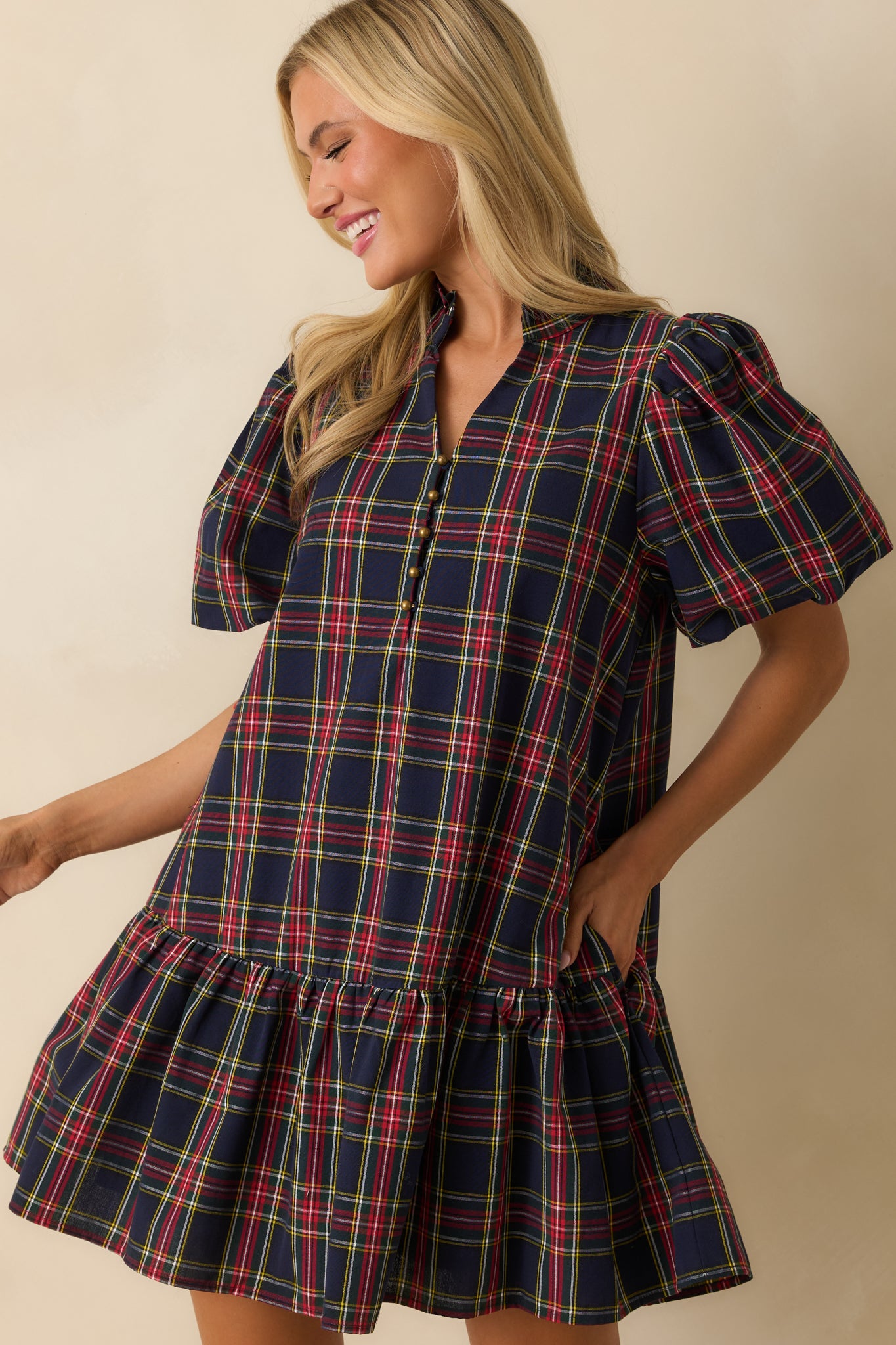 Front-focused crop highlighting ruffled drop hem and side pocket on the navy plaid dress.