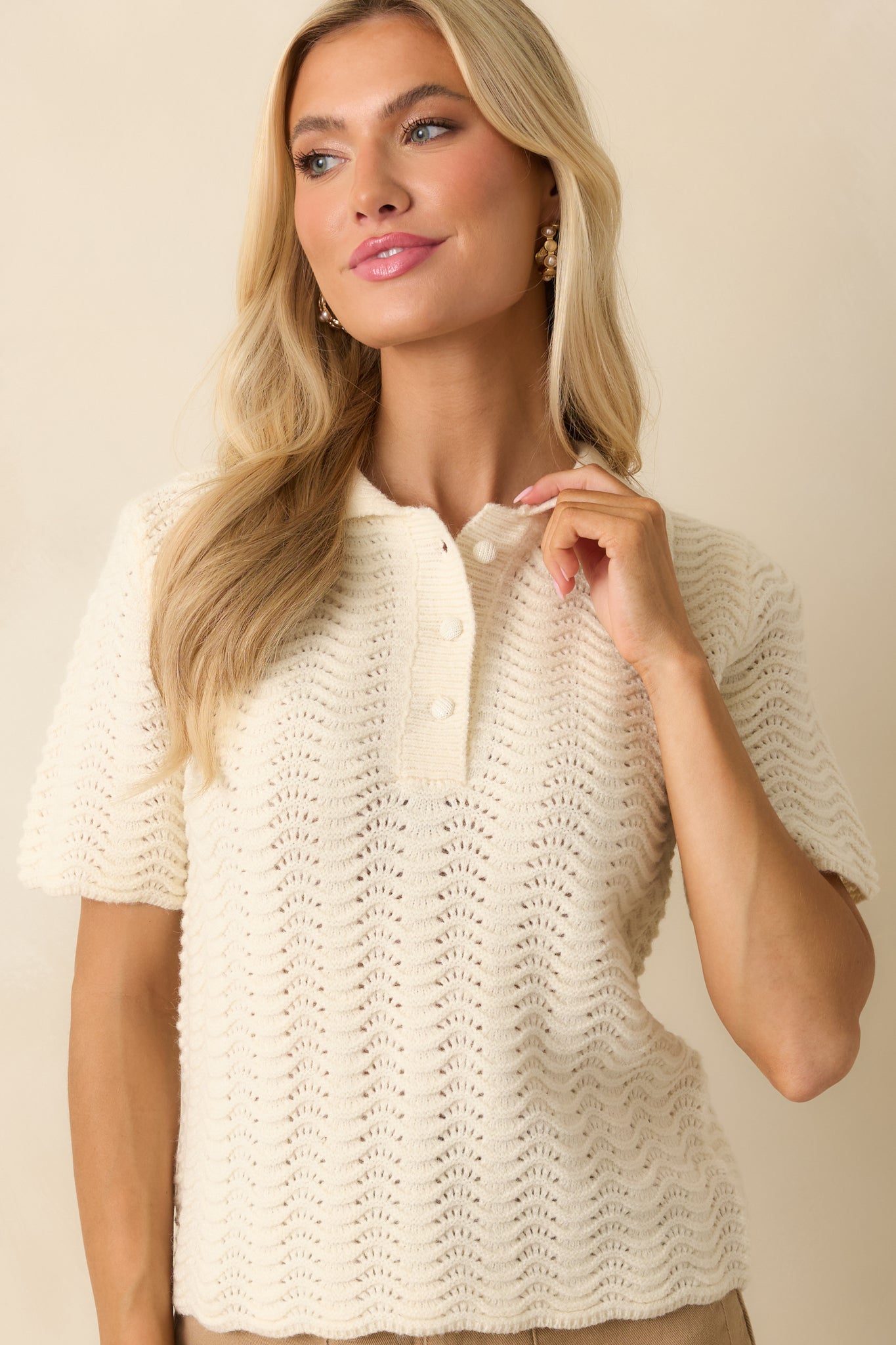 Cropped front view focusing on the ribbed buttoned placket and scalloped knit detailing.