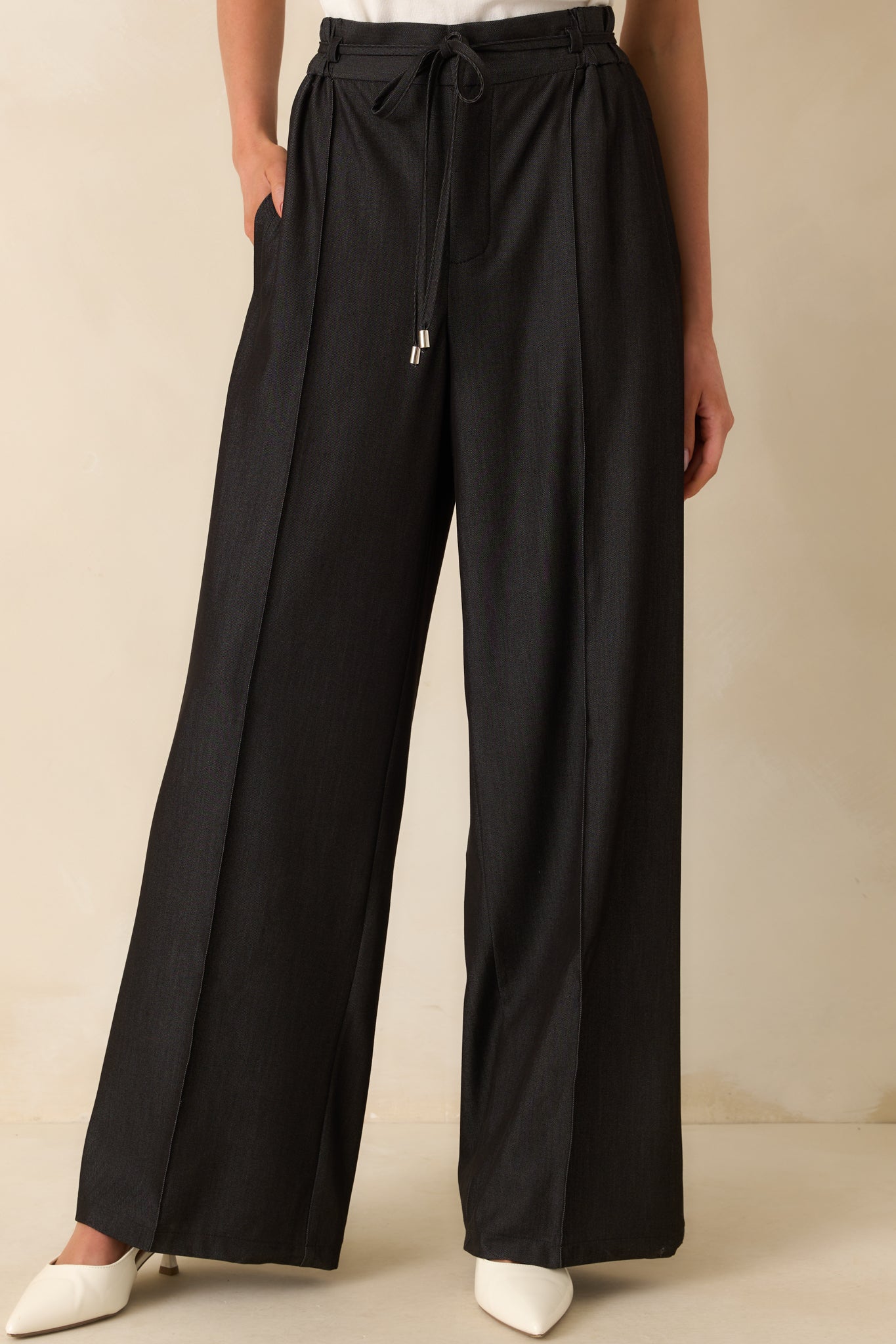 Cropped front view focused on the waistband, showing the hook and bar button closure and small belt loops.