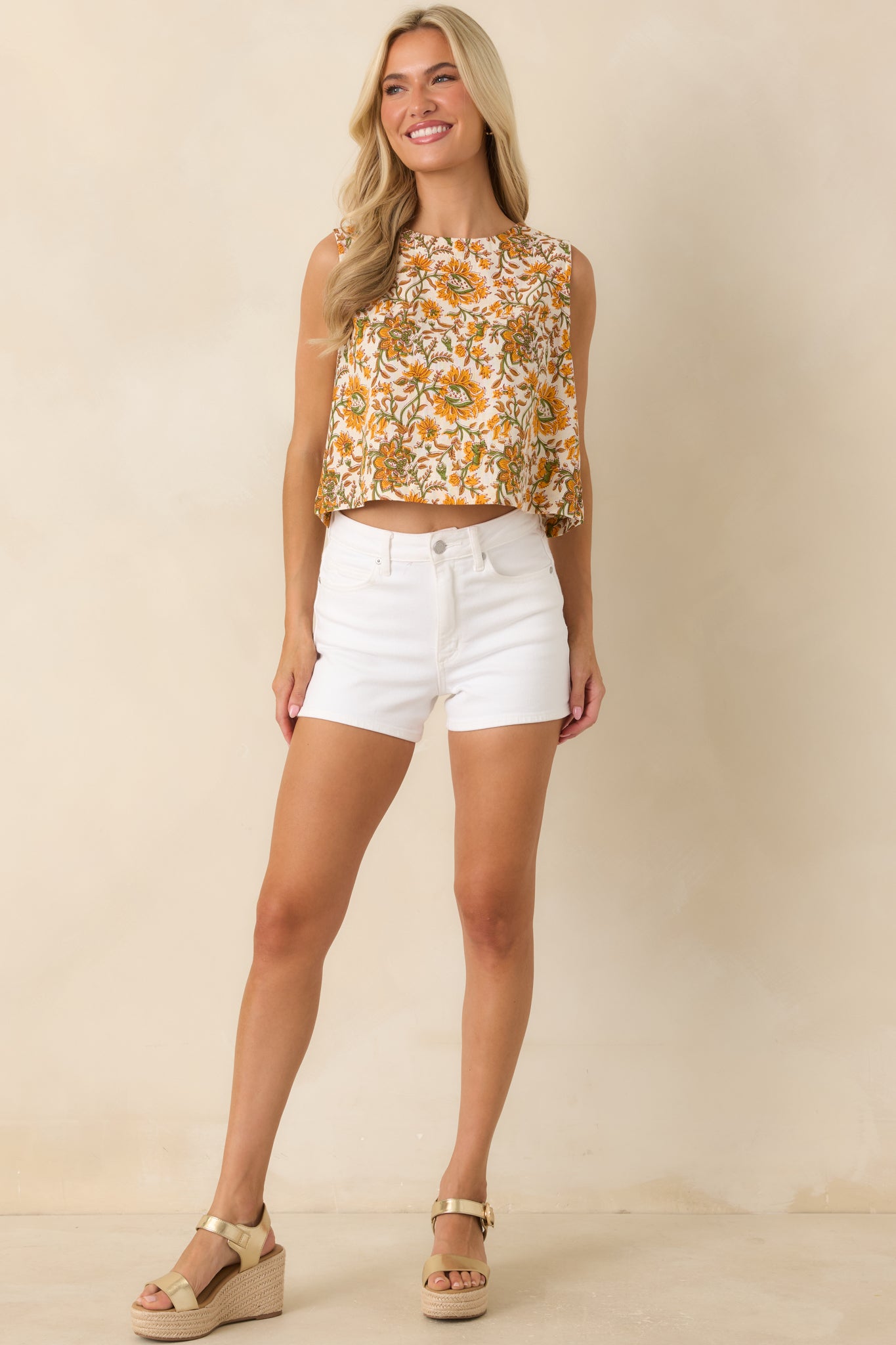 Front-facing view emphasizing the cropped silhouette, high neckline, and intricate floral design throughout the ivory sleeveless top.
