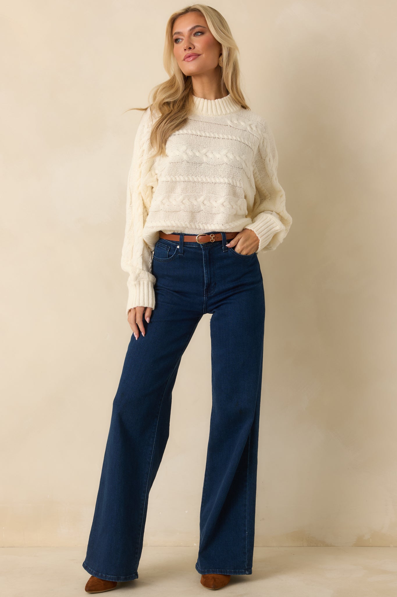 Cropped ivory sweater highlighting mixed cable knit patterns across the body and sleeves.