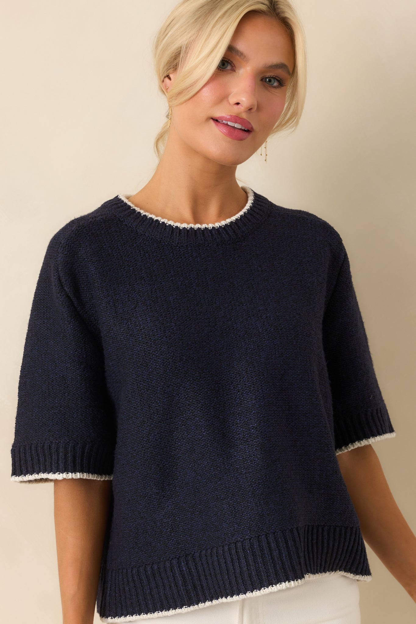 Cropped image showing ribbed hem and textured knit fabric of navy sweater.
