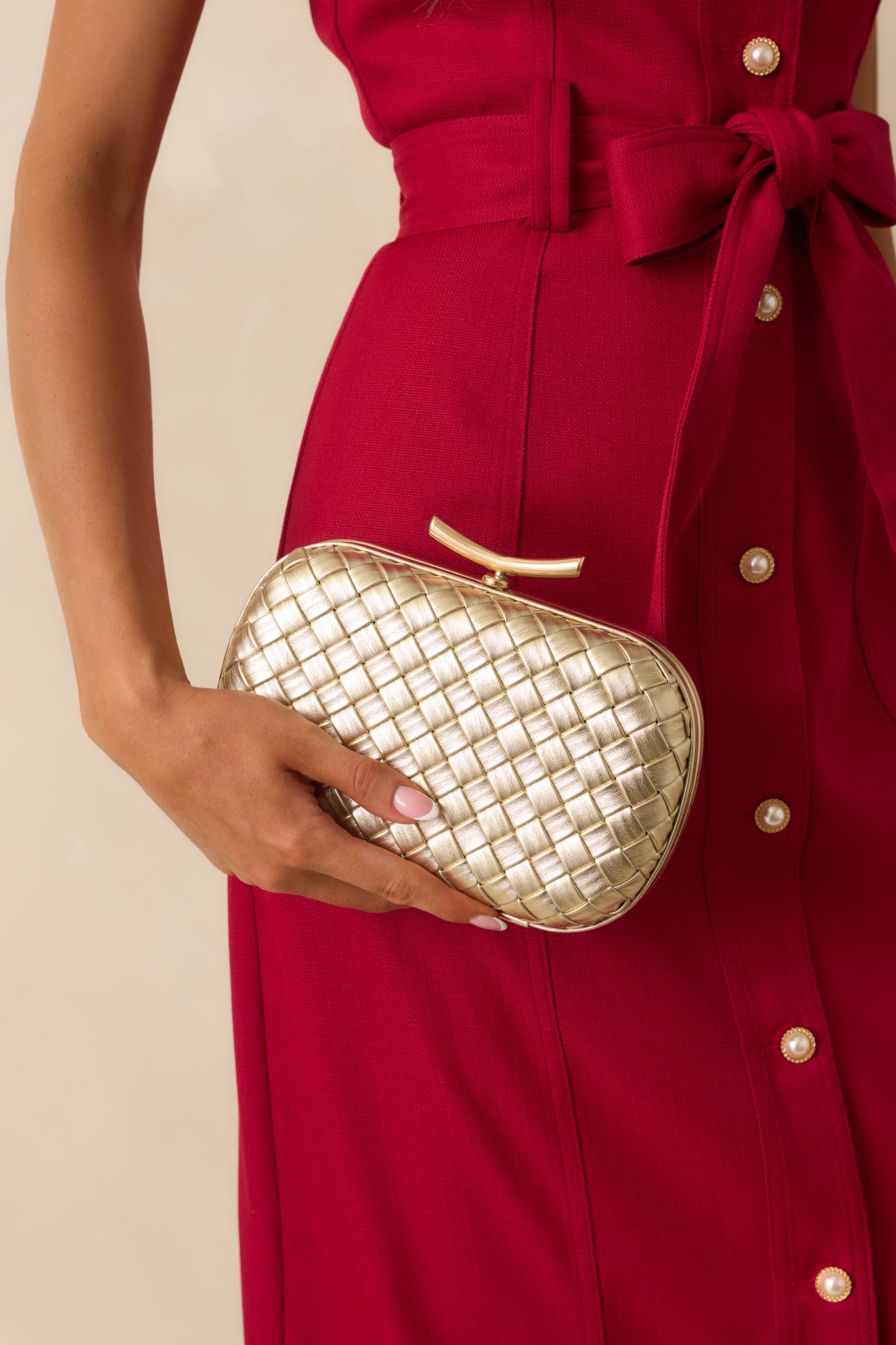 Cropped in photo focusing on the metallic woven texture and rounded edge detail of the clutch.
