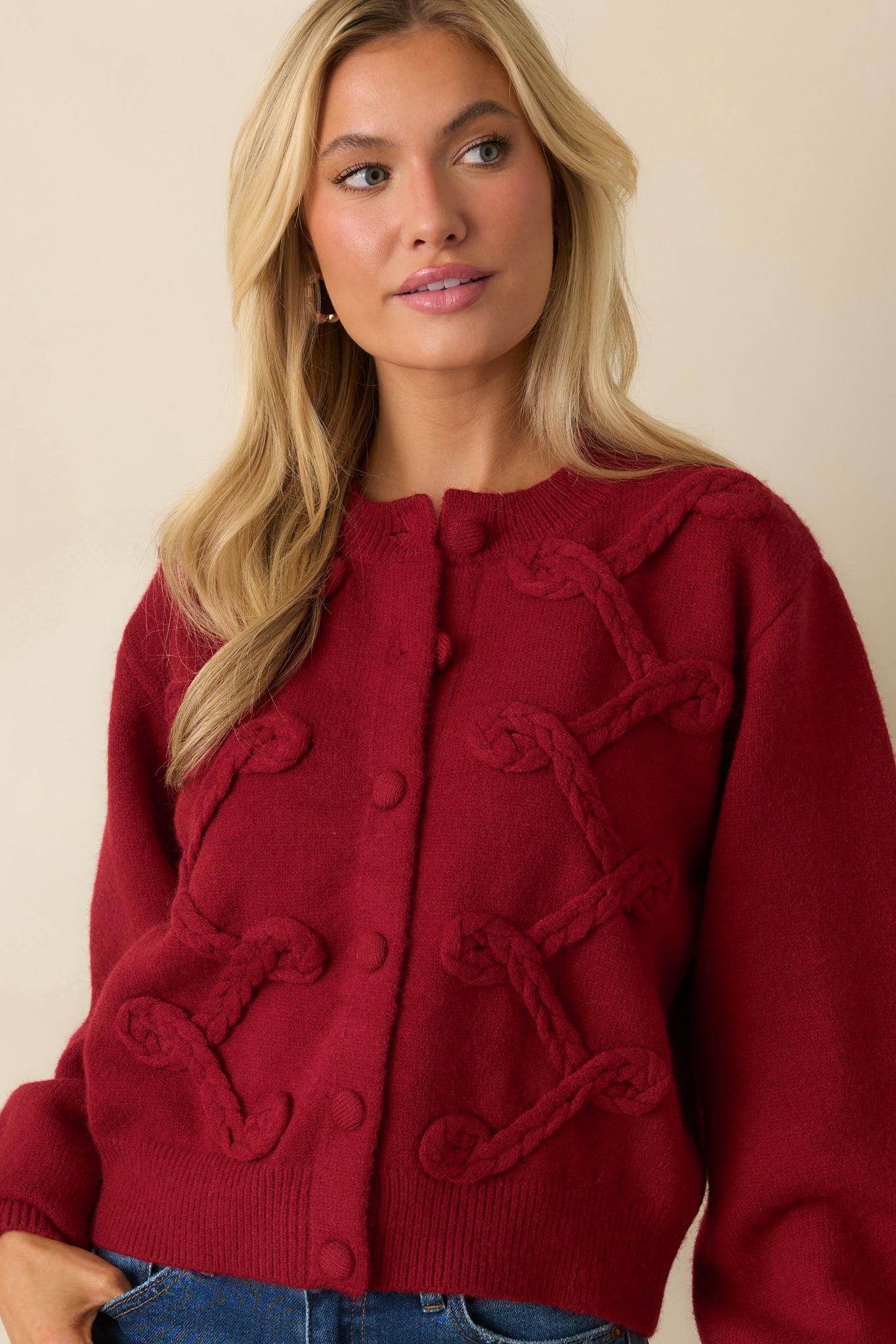 Cropped view highlighting ribbed trim, round neckline, and button closure details on the red cardigan.