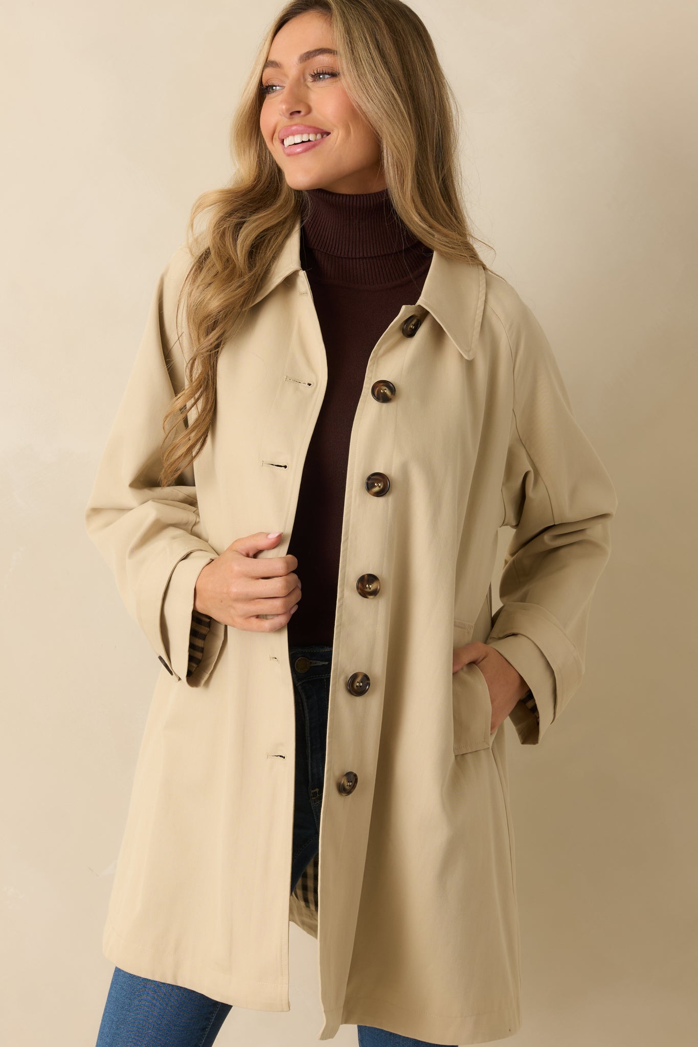 Cropped shot emphasizing button details, collar, and classic trench styling.