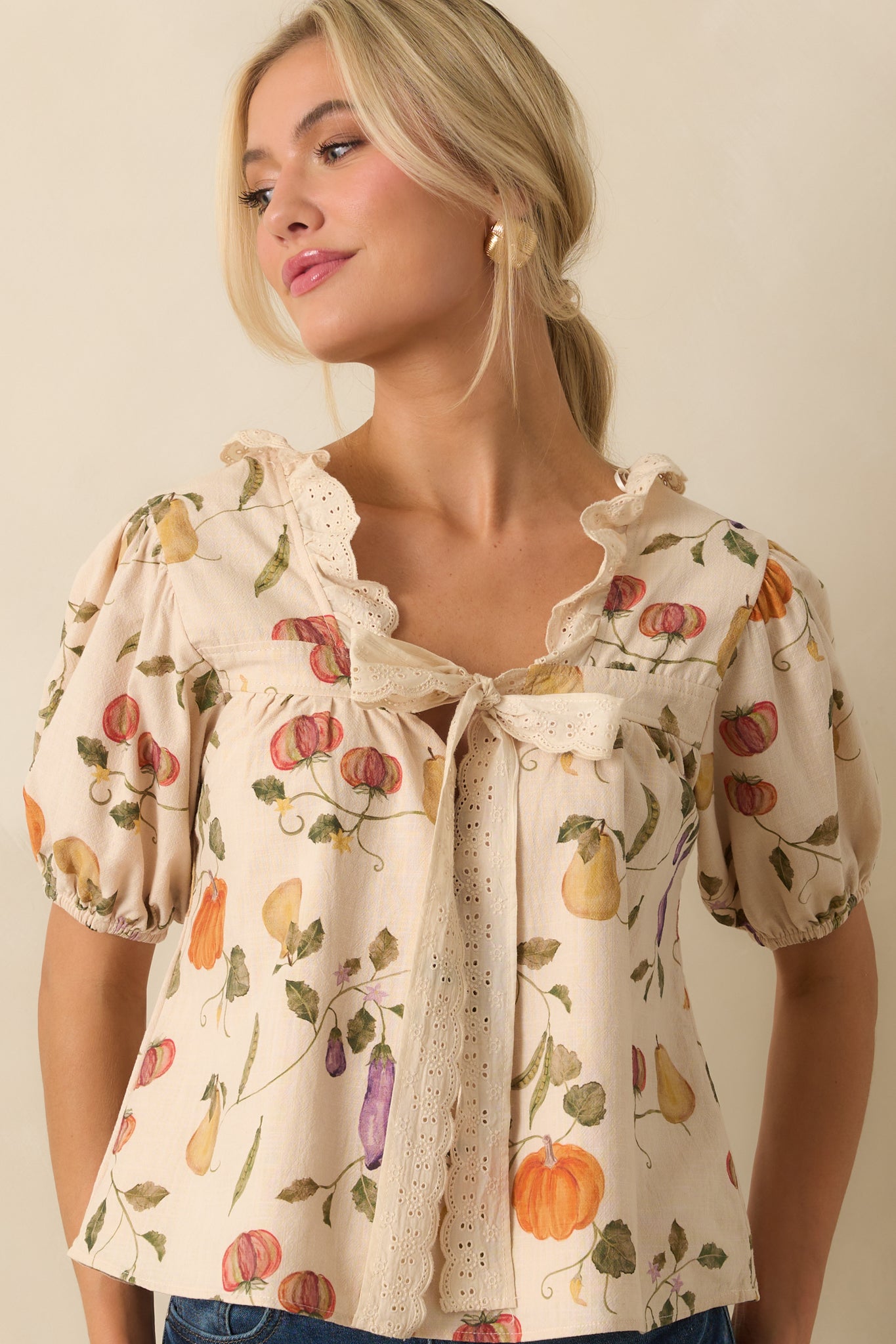 Cropped front shot of ivory top highlighting colorful vegetable garden pattern and bow-tie front.