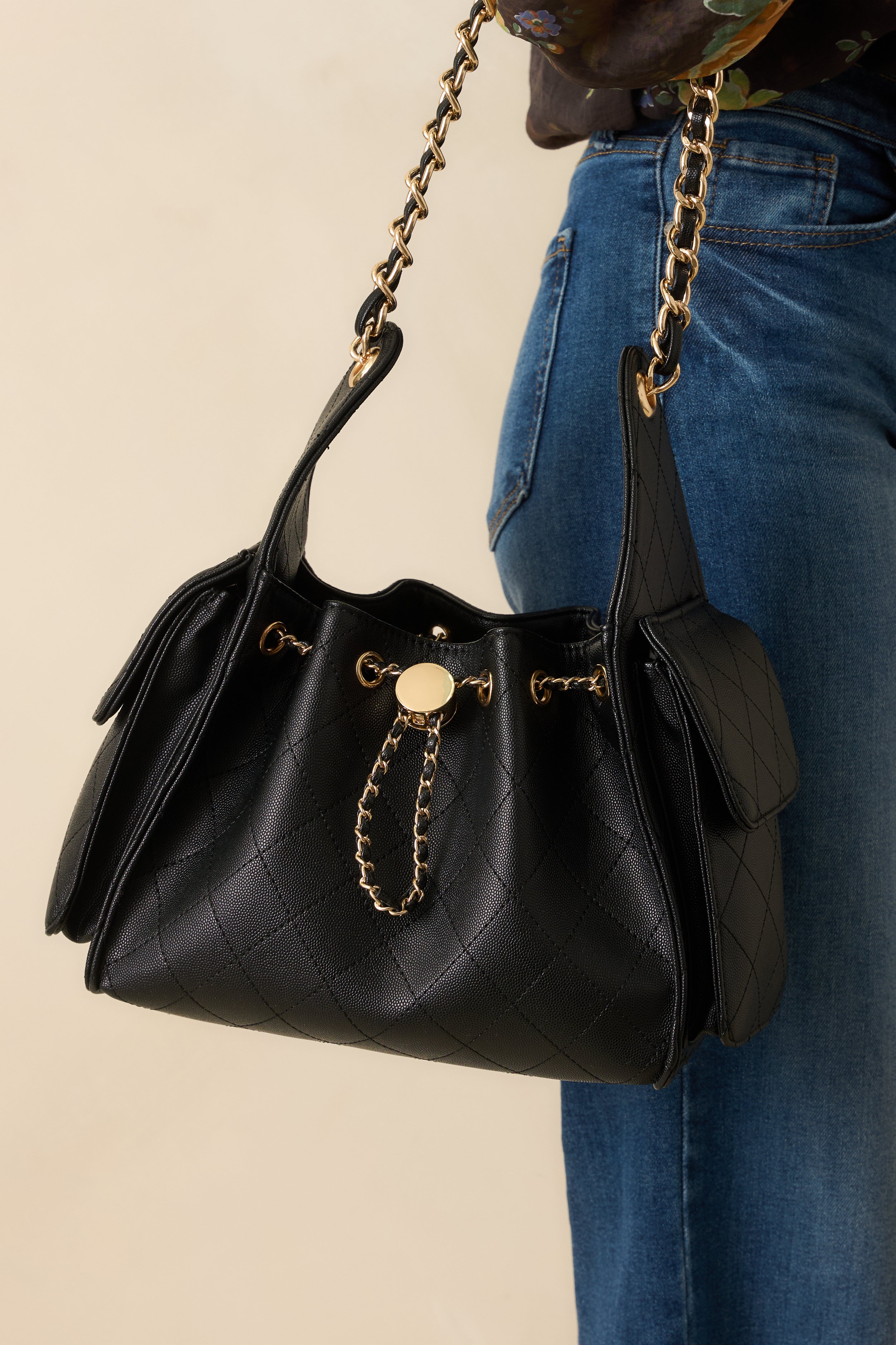 Cropped side view showing the large pocket with fold-over flap and gold chain strap detail.