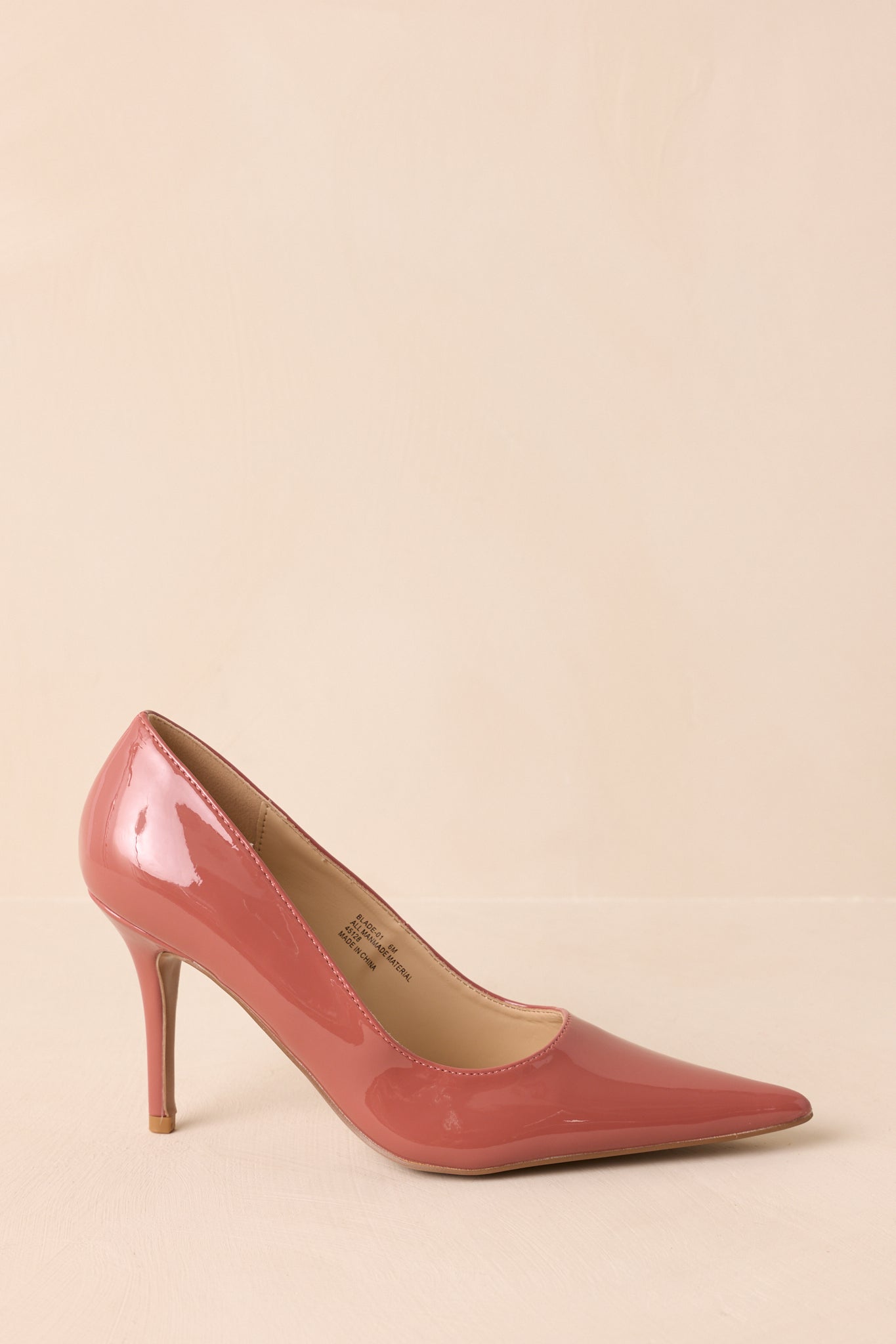 Cropped side view highlighting the pointed toe and glossy blush patent finish.