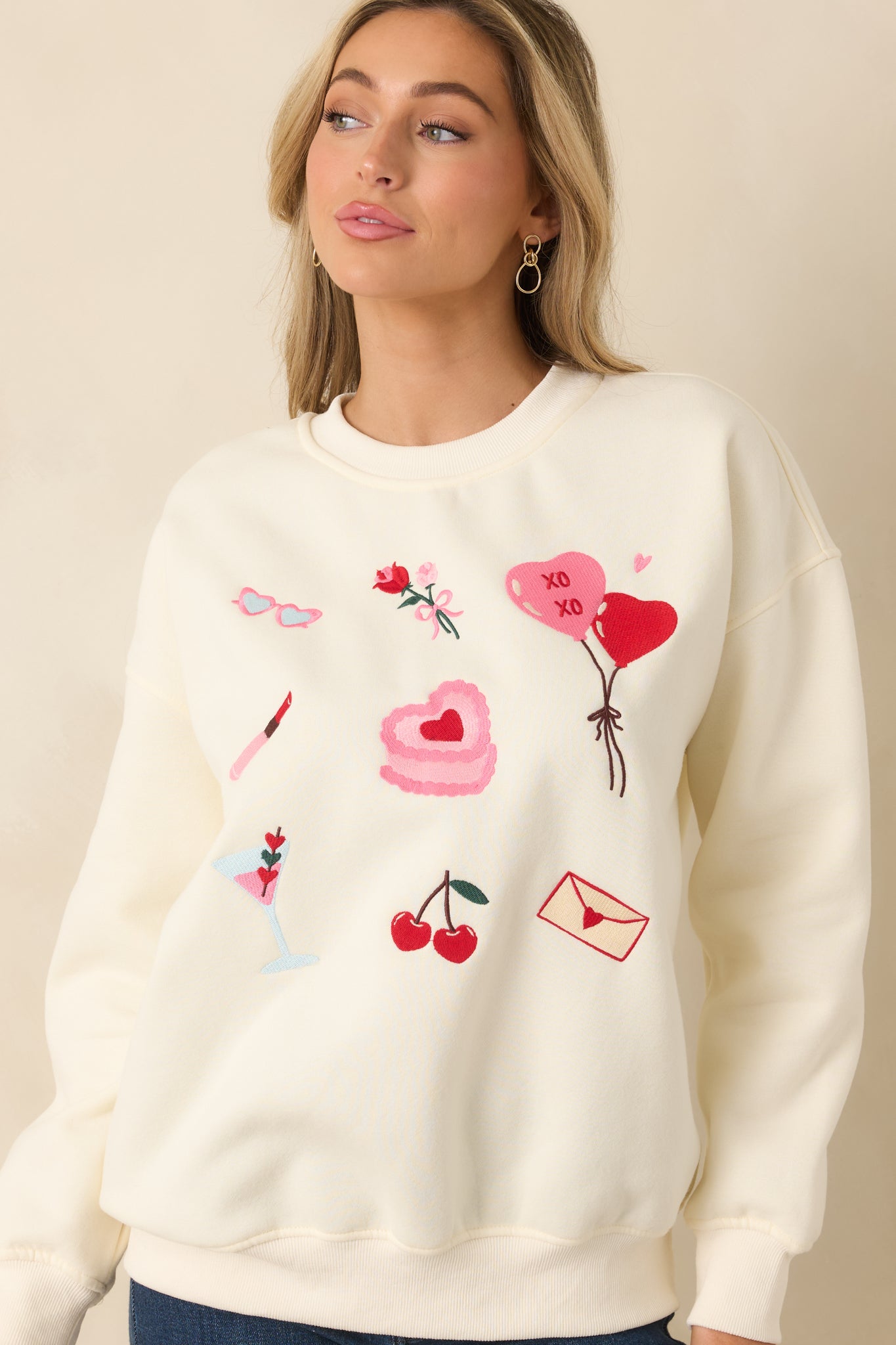 Close cropped view emphasizing the ribbed cuffs and midweight knit texture of the ivory sweatshirt.