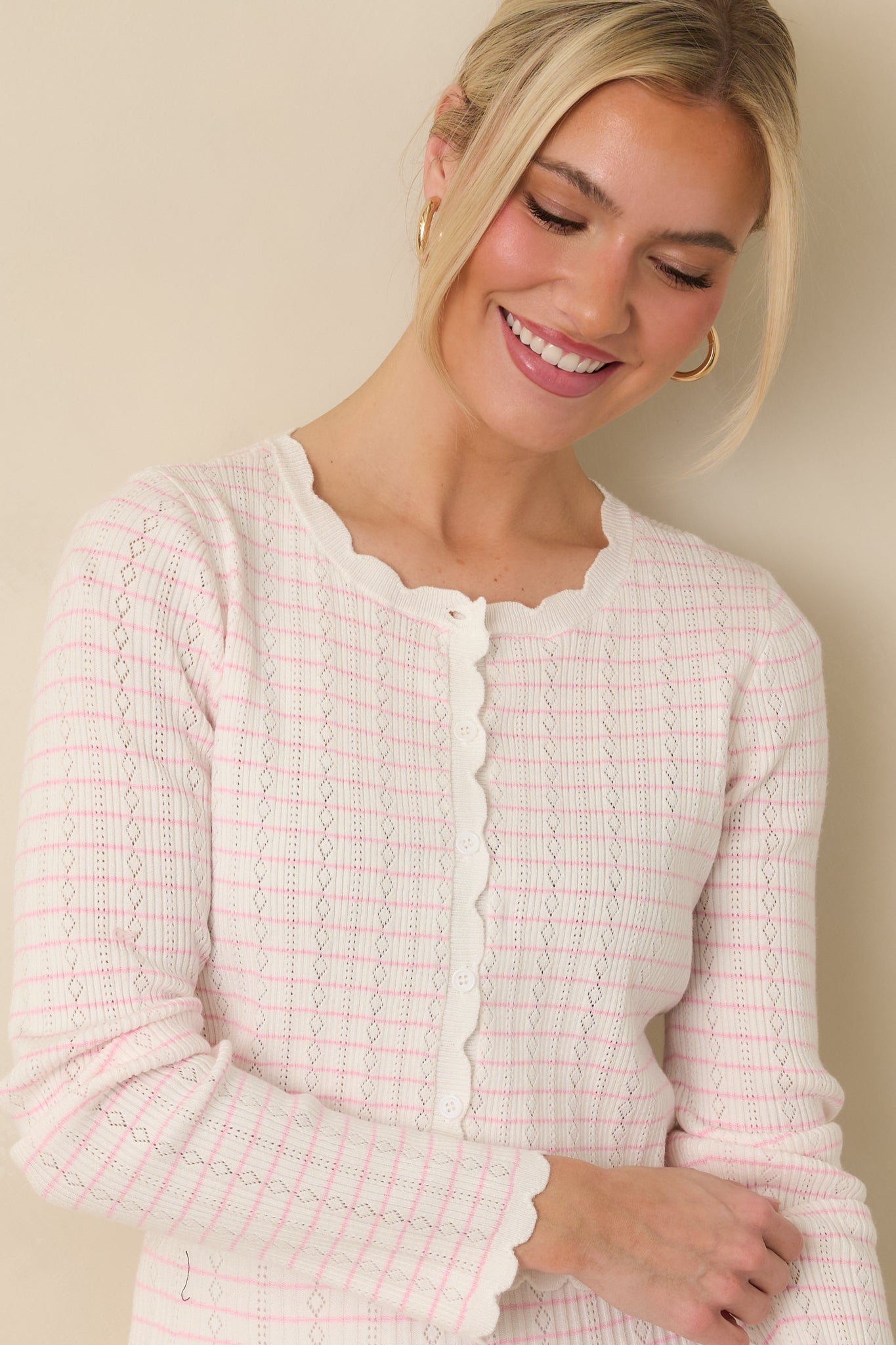 Cropped front view of the white cardigan focusing on the pink stripe pattern and round neckline.