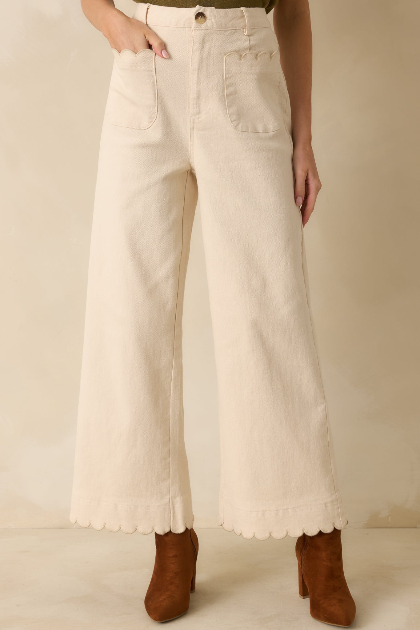 Cropped view of pants’ upper front showing high-waist, belt loops, and scalloped-trim patch pockets.