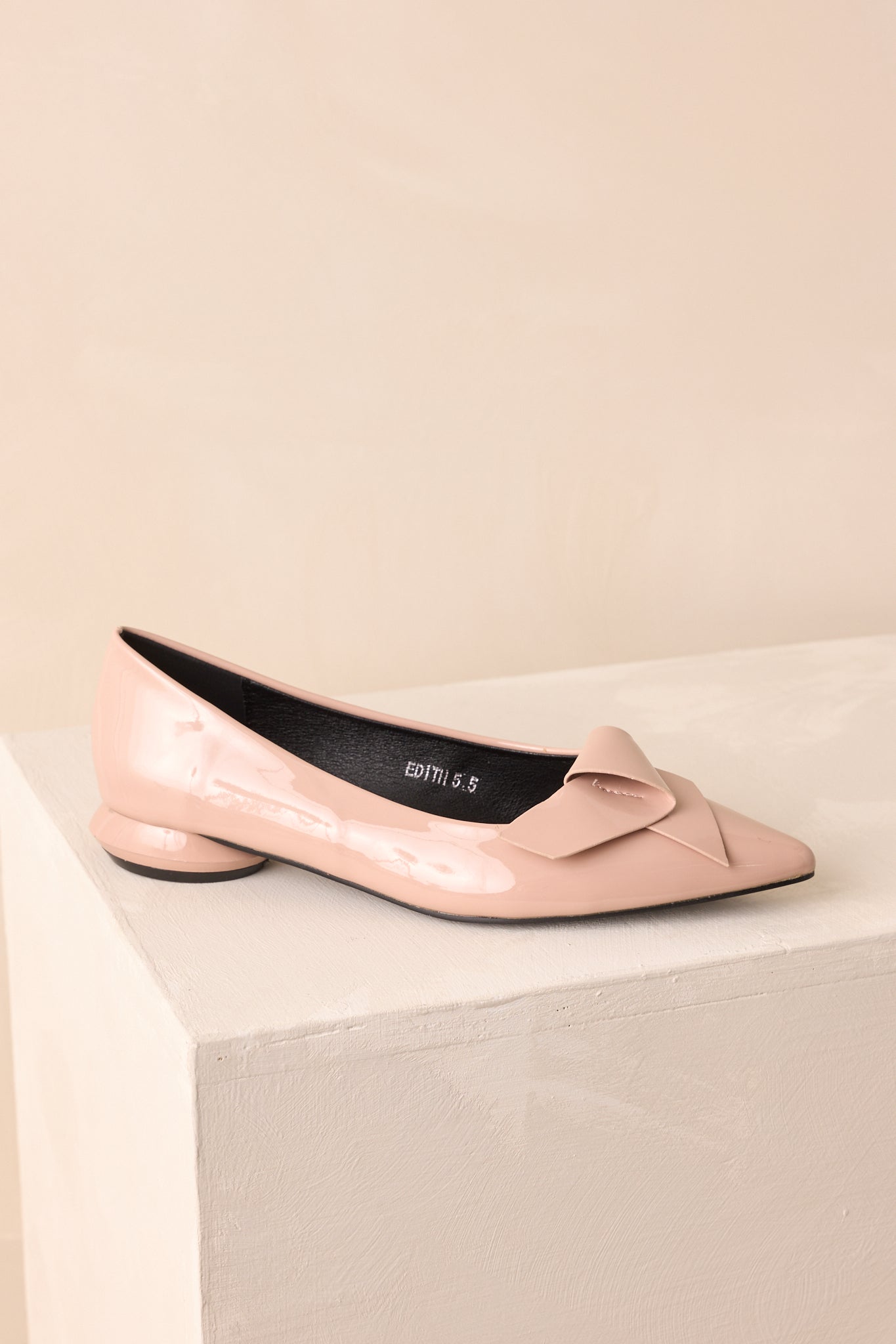 Cropped view of the beige patent flats, highlighting the folded bow detail across the vamp.
