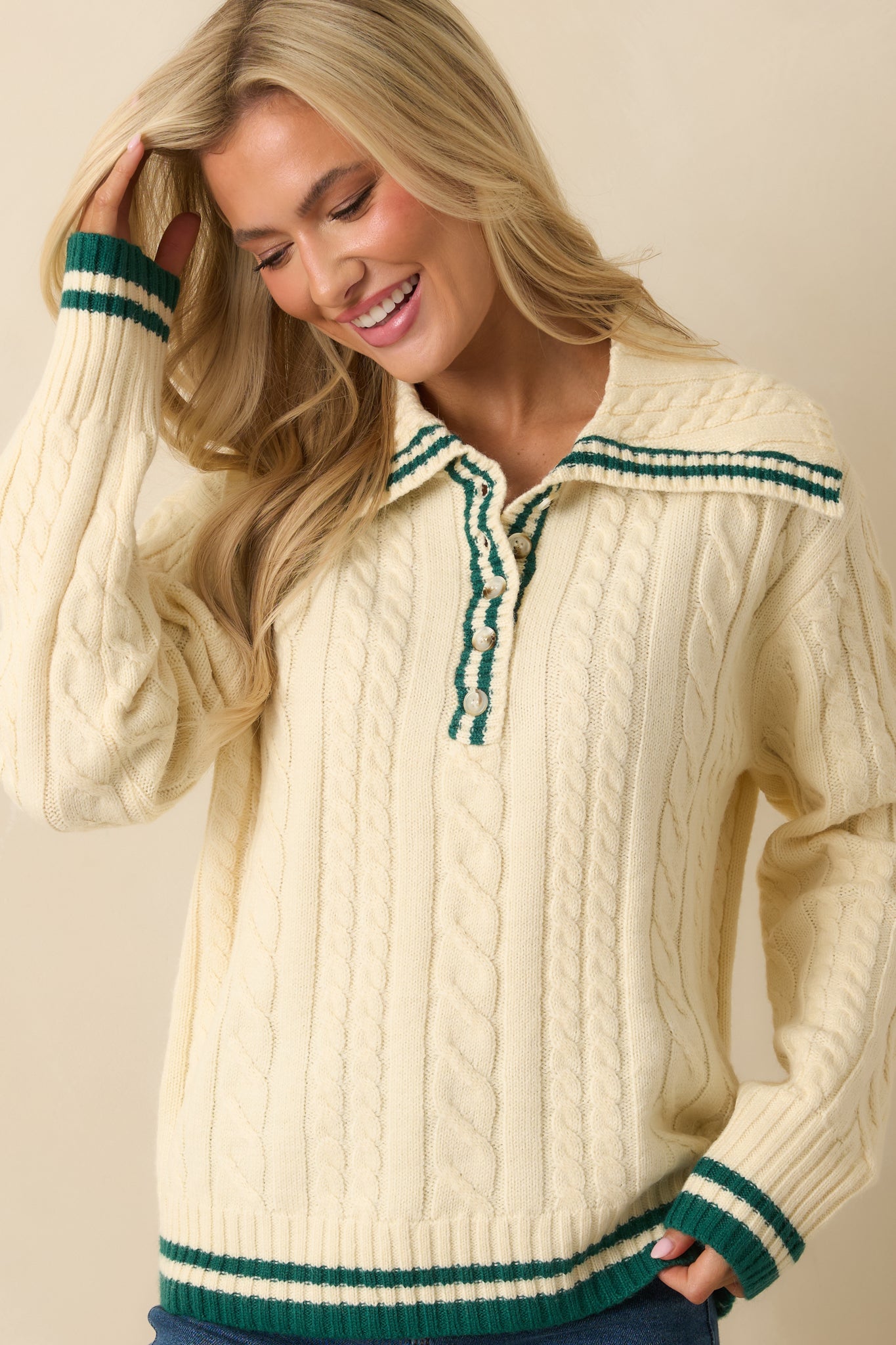 Cropped view of ivory cable knit sweater, highlighting ribbed hem, cuffs, and soft textured fabric.