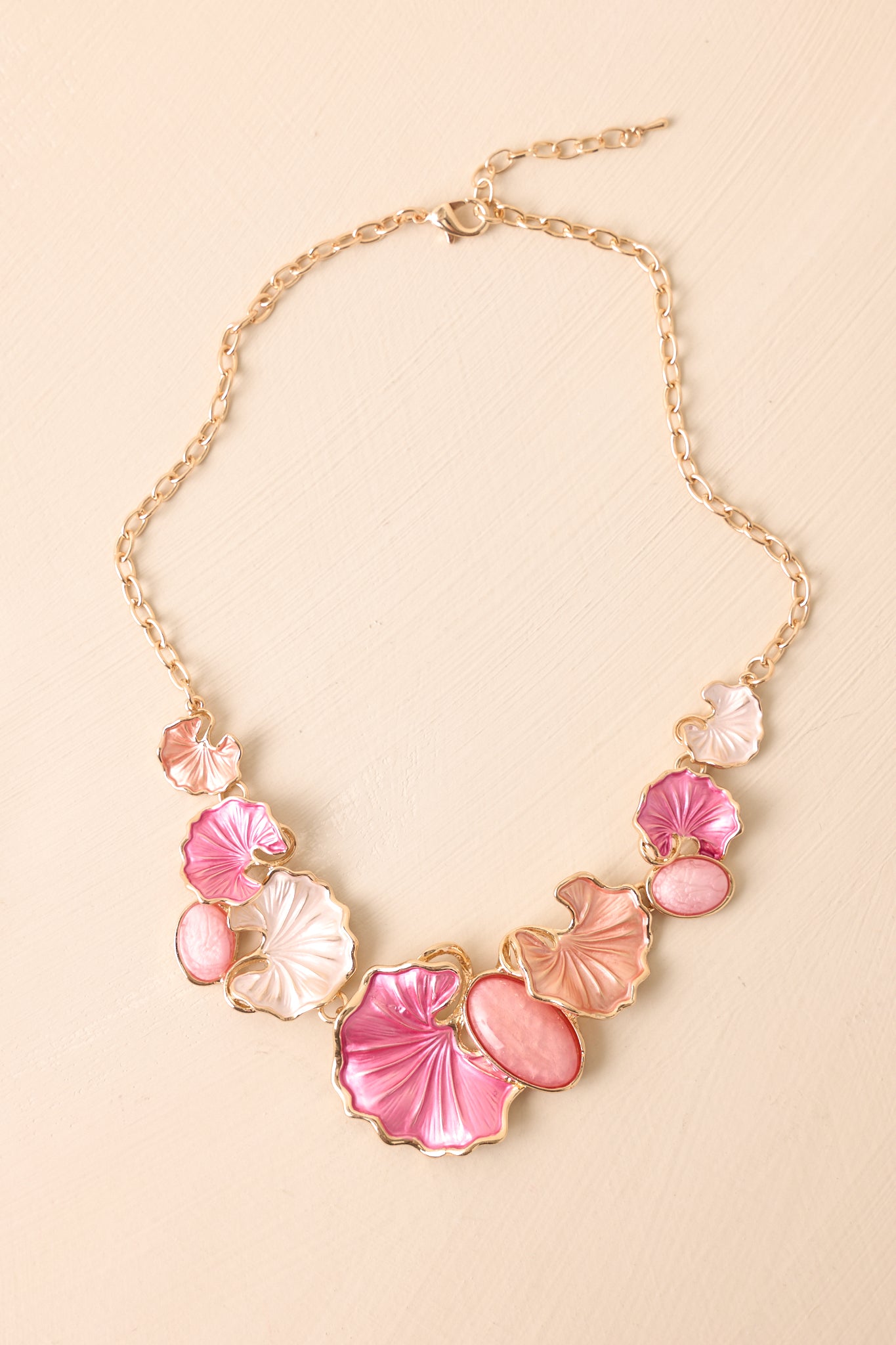 Cropped view of pink statement necklace with multicolor pearlescent flower petal charms and cabochon accents.