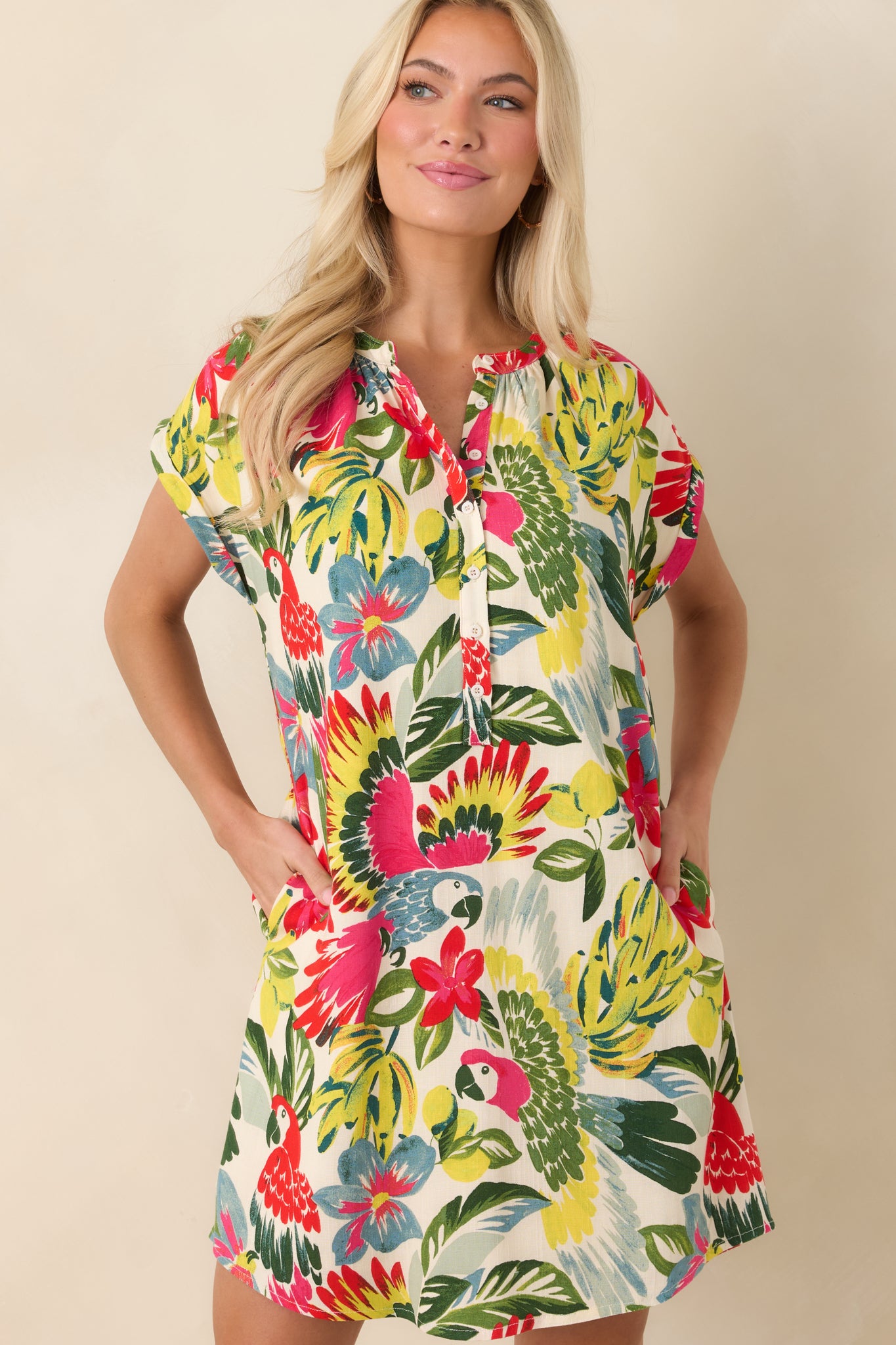 Cropped view of red parrot-print mini dress highlighting button-front neckline and cap sleeves