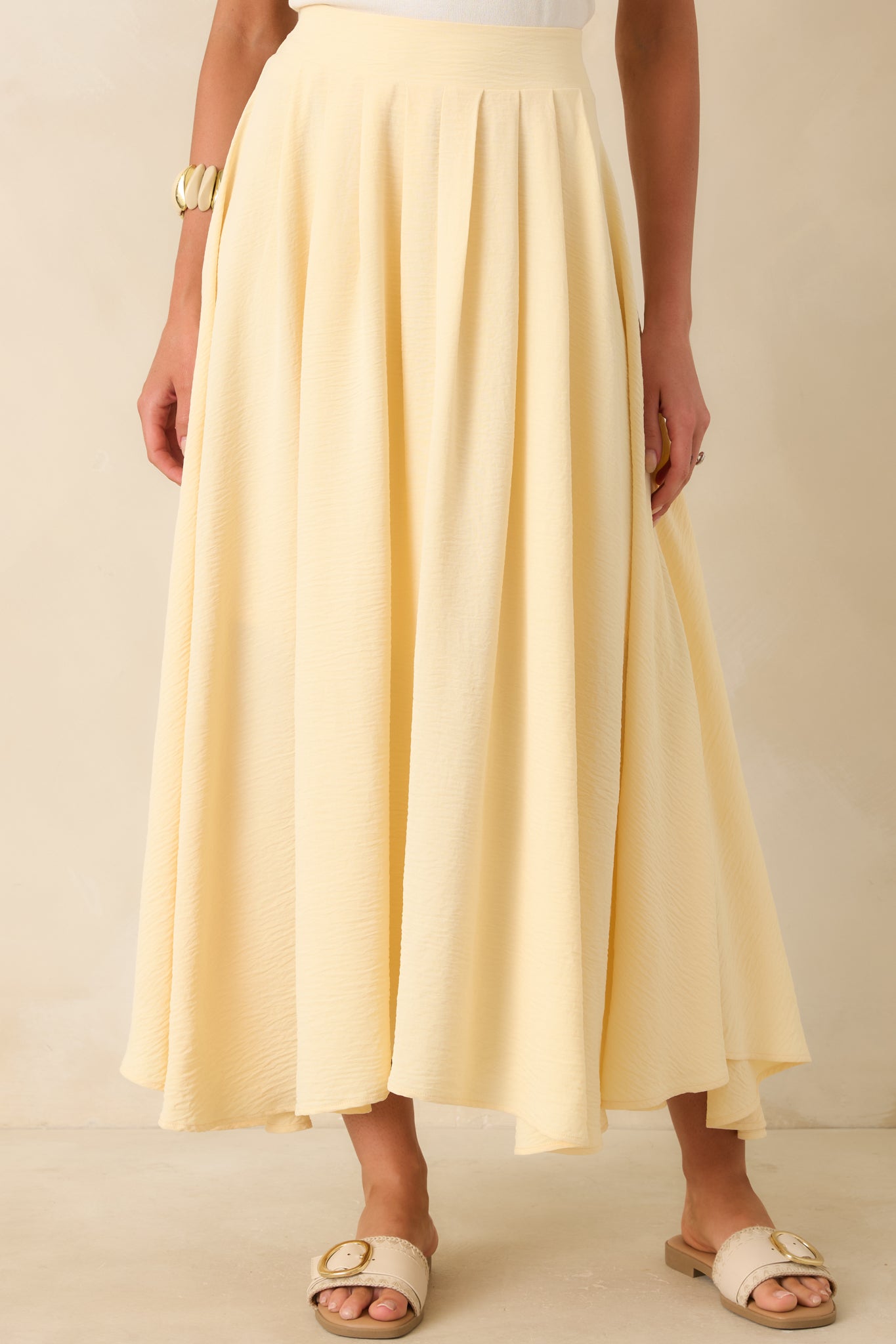 Close cropped view of the light yellow maxi skirt with a full lining and relaxed drape.
