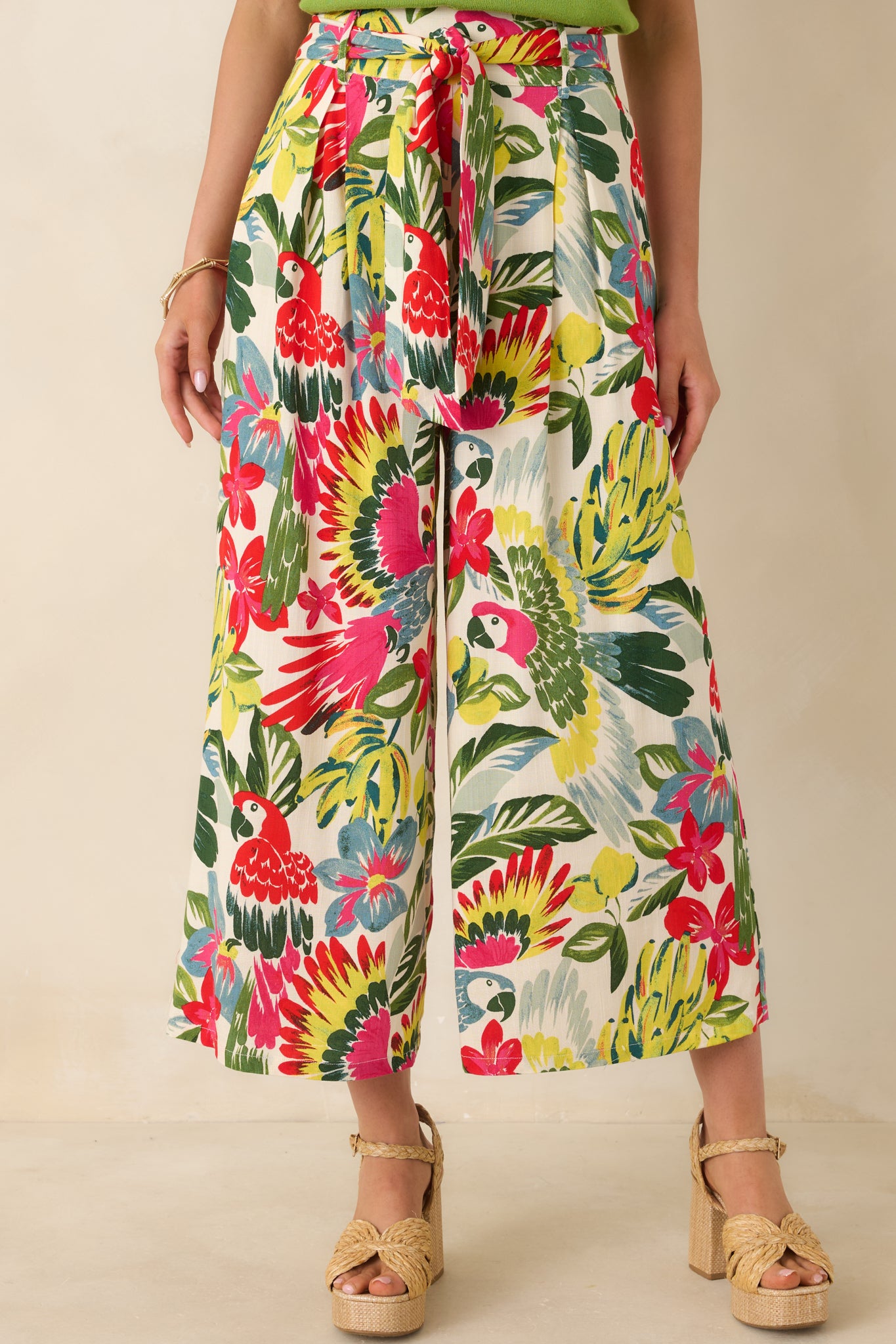 Cropped view of tropical print pants highlighting self-tie waist belt and vibrant parrot pattern