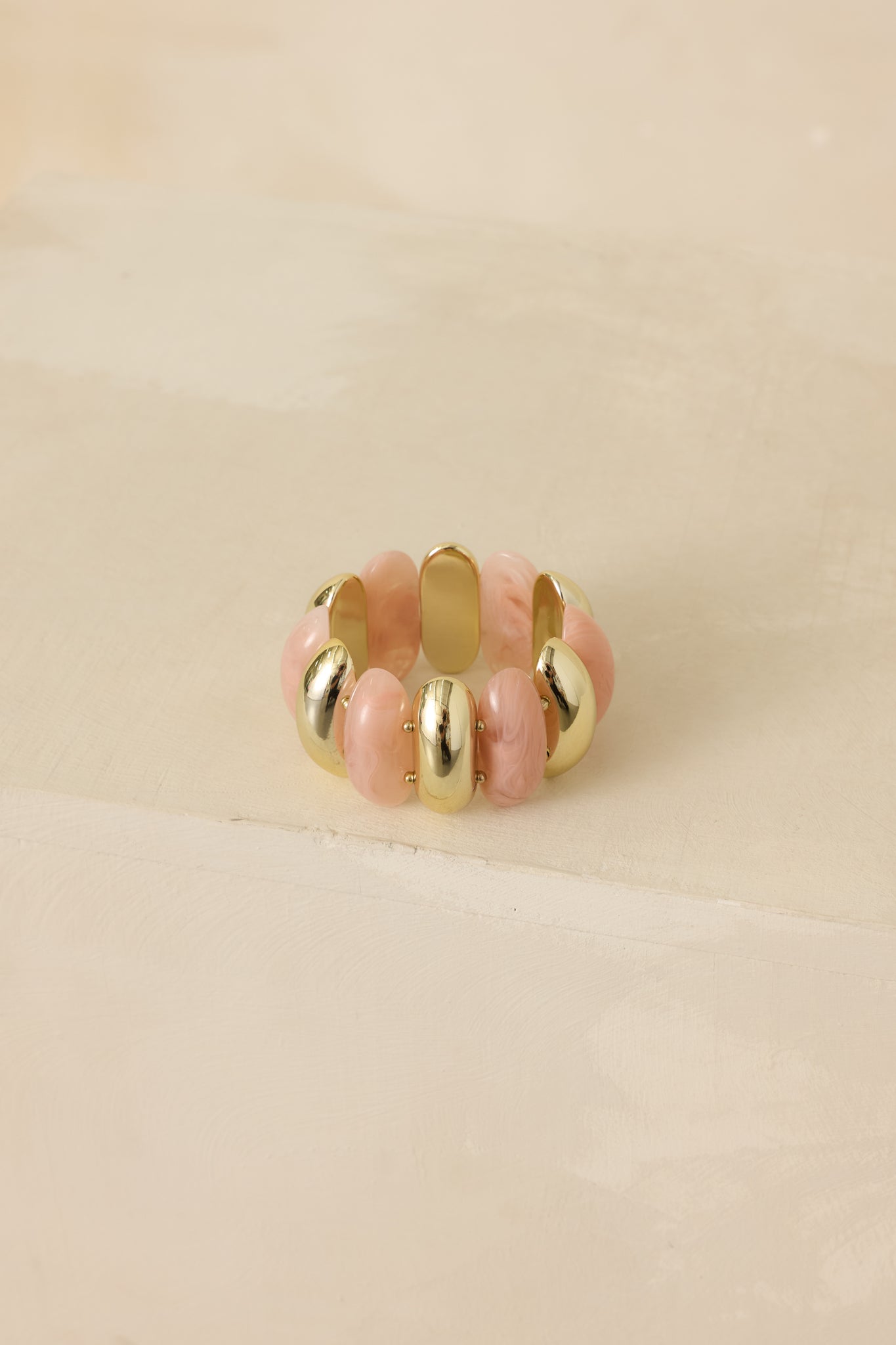 Cropped view of the pink and gold double-row stretch bracelet showing alternating faux rose quartz–style beads and shiny gold accents.