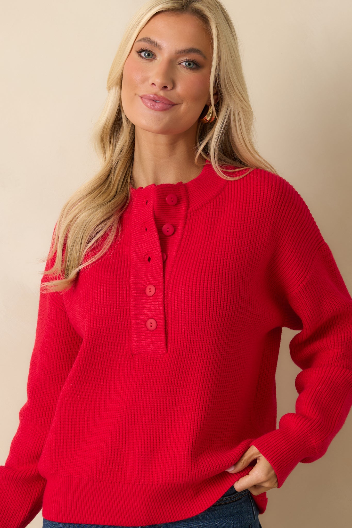 Cropped view focusing on the dropped shoulders and soft ribbed detailing of red knit sweater.