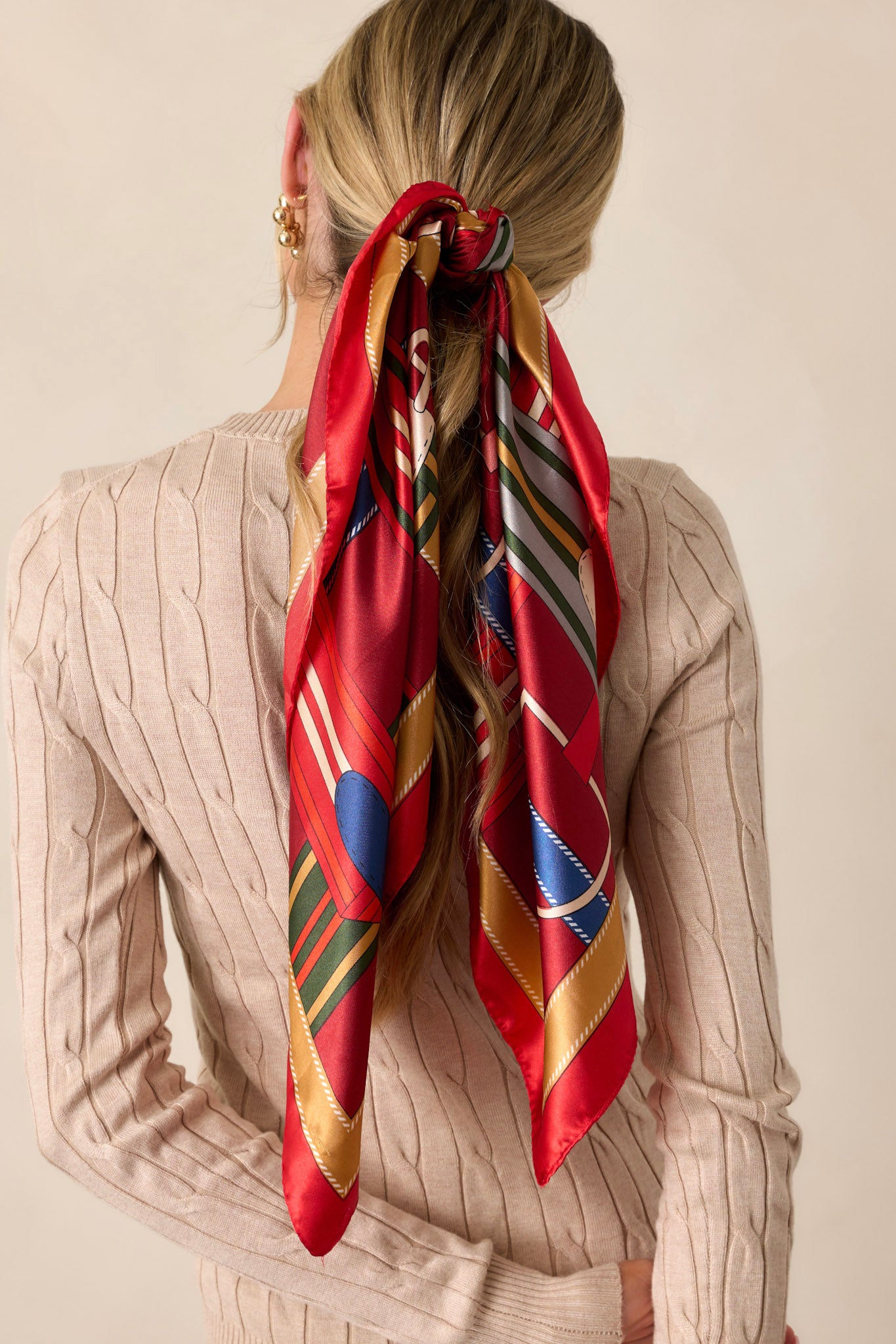 A cropped image of the red scarf tied in the hair, showcasing its vibrant red hue and glossy texture.