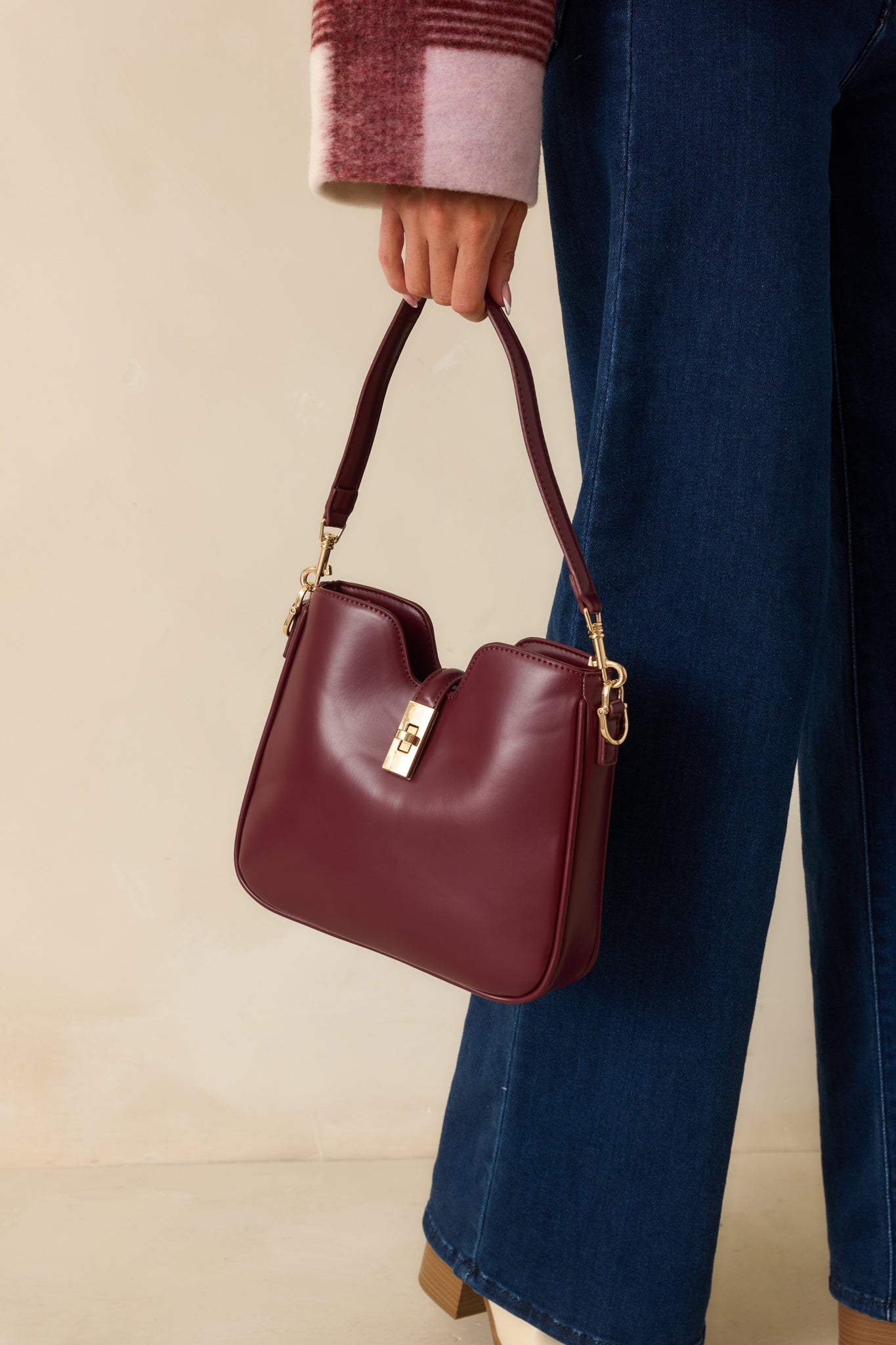 Angled cropped view of the handbag showcasing the structured shape and glossy wine red surface.