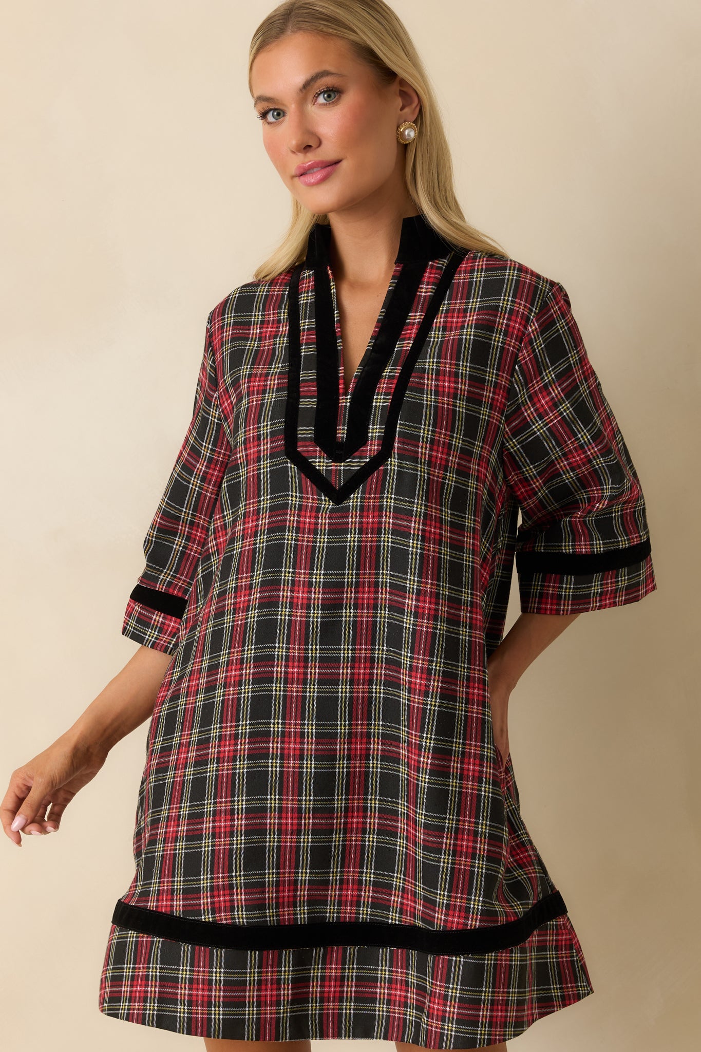 Cropped focus on side pocket, fabric texture, and black velvet trim on the red and black plaid dress.