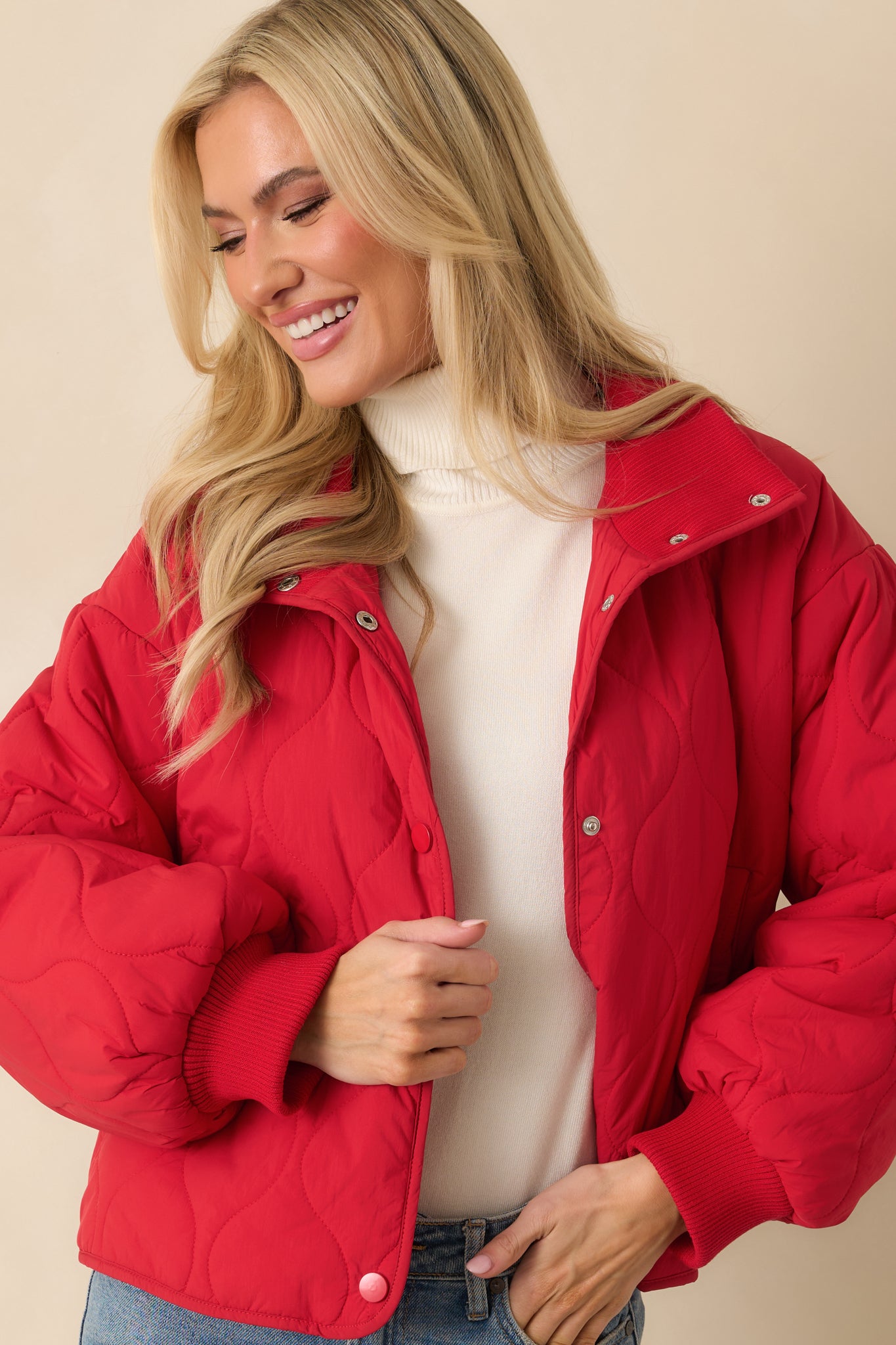 Cropped view focusing on the snap-front buttons and structured stand collar of the red quilted jacket.