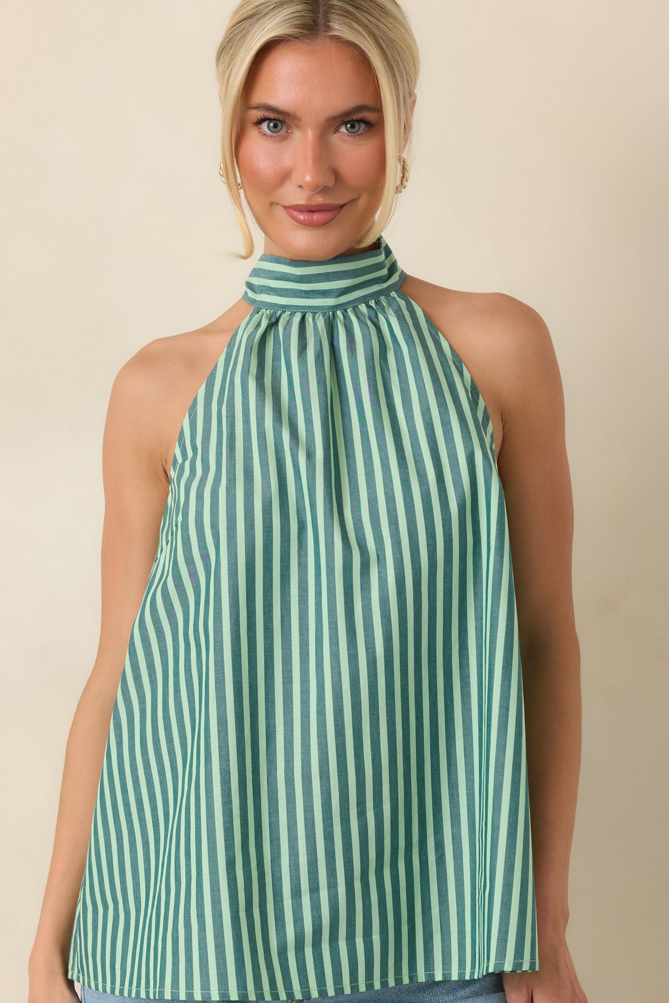 Alternating dark green and mint stripes emphasize the airy cotton fabric and relaxed silhouette of the sleeveless halter top.