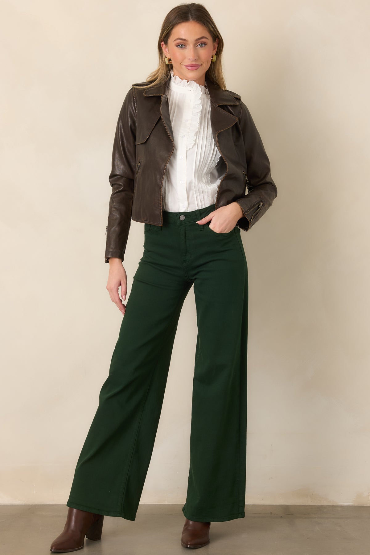 Cropped dark brown jacket defined by an open front, broad notched lapels, zippered side pockets, and sleek faux leather finish.
