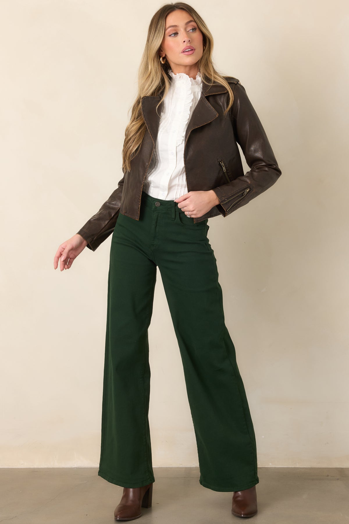 Dark brown faux leather jacket featuring a cropped silhouette, wide notched lapels, open front, long sleeves, and zippered side pockets.