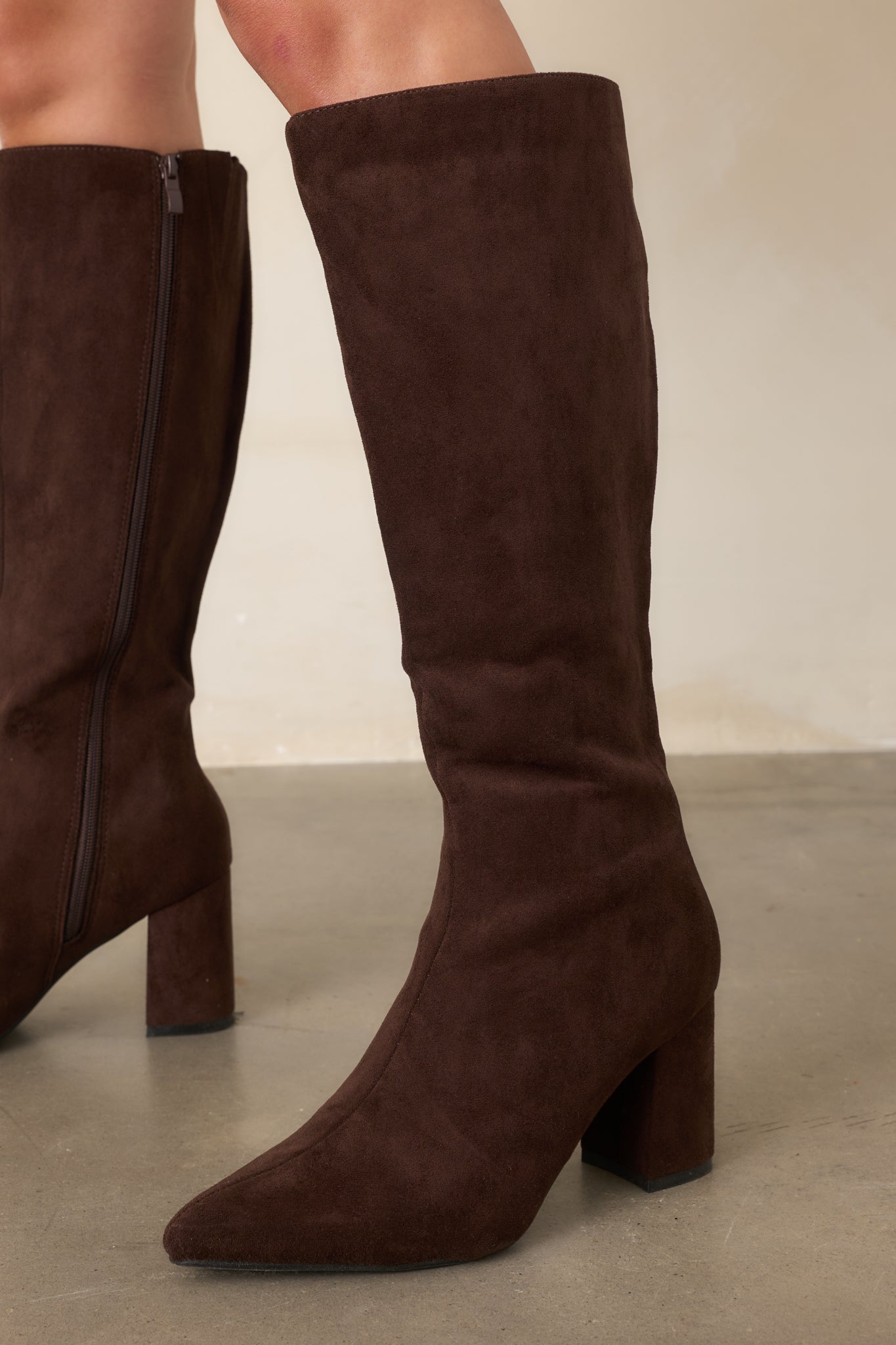 Tall dark brown faux suede boots with pointed toes, fitted knee-high shafts, and covered block heels.