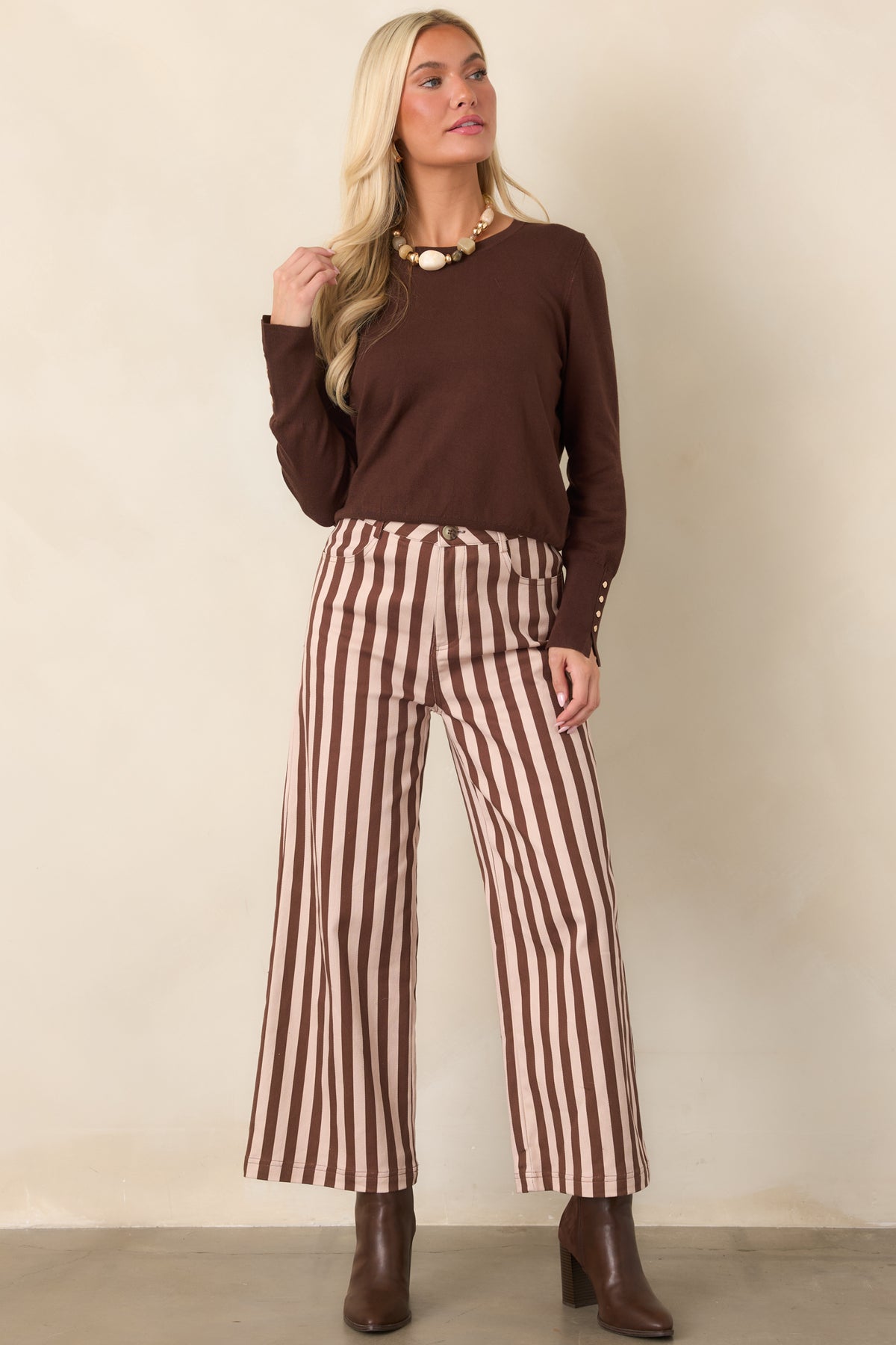Dark brown everyday top with a simple crew neck, elongated sleeves, ribbed hem, and refined gold-tone button details at the cuffs.