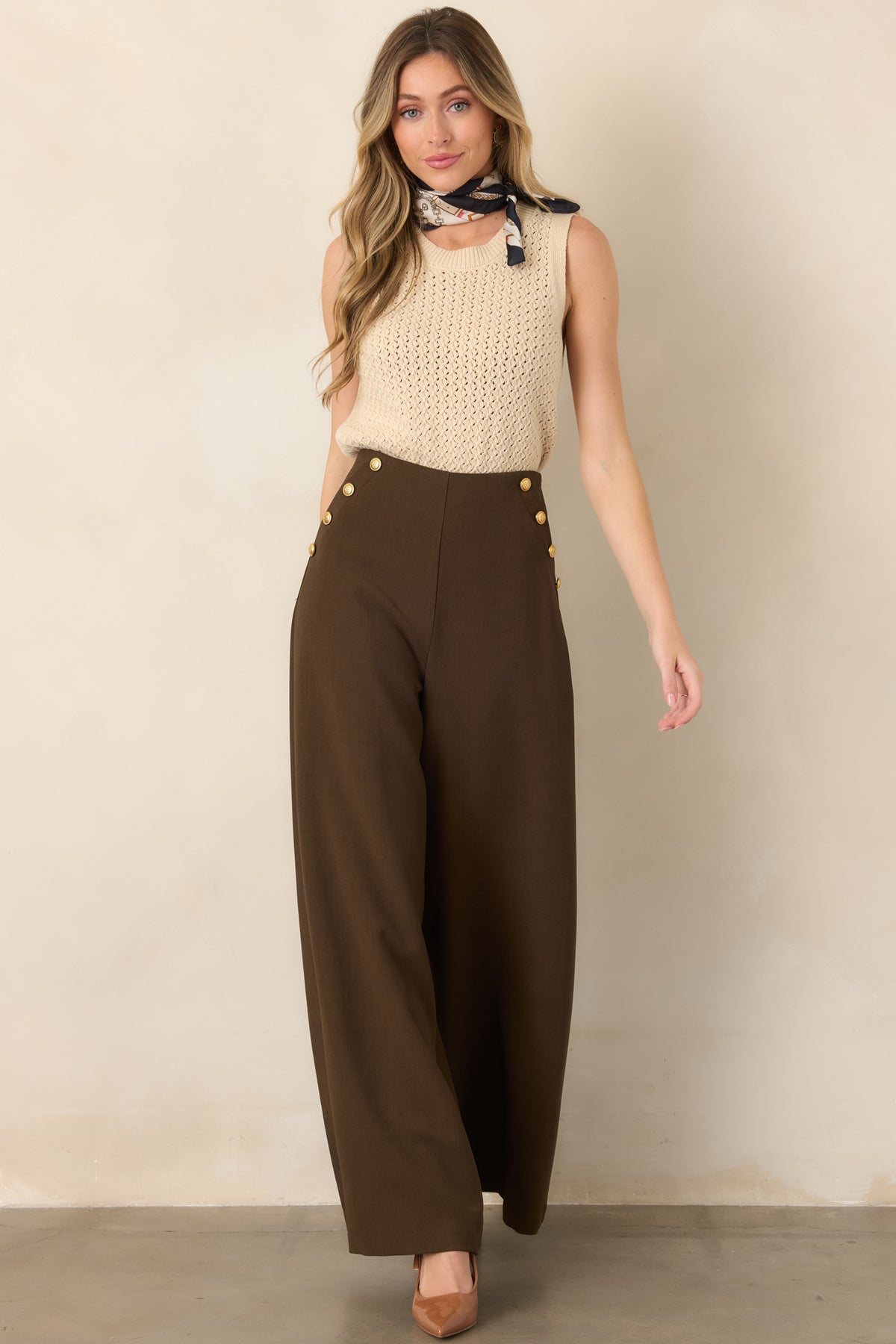Dark brown tailored pants with a smooth woven finish, prominent hip button detailing, and a polished wide-leg shape.
