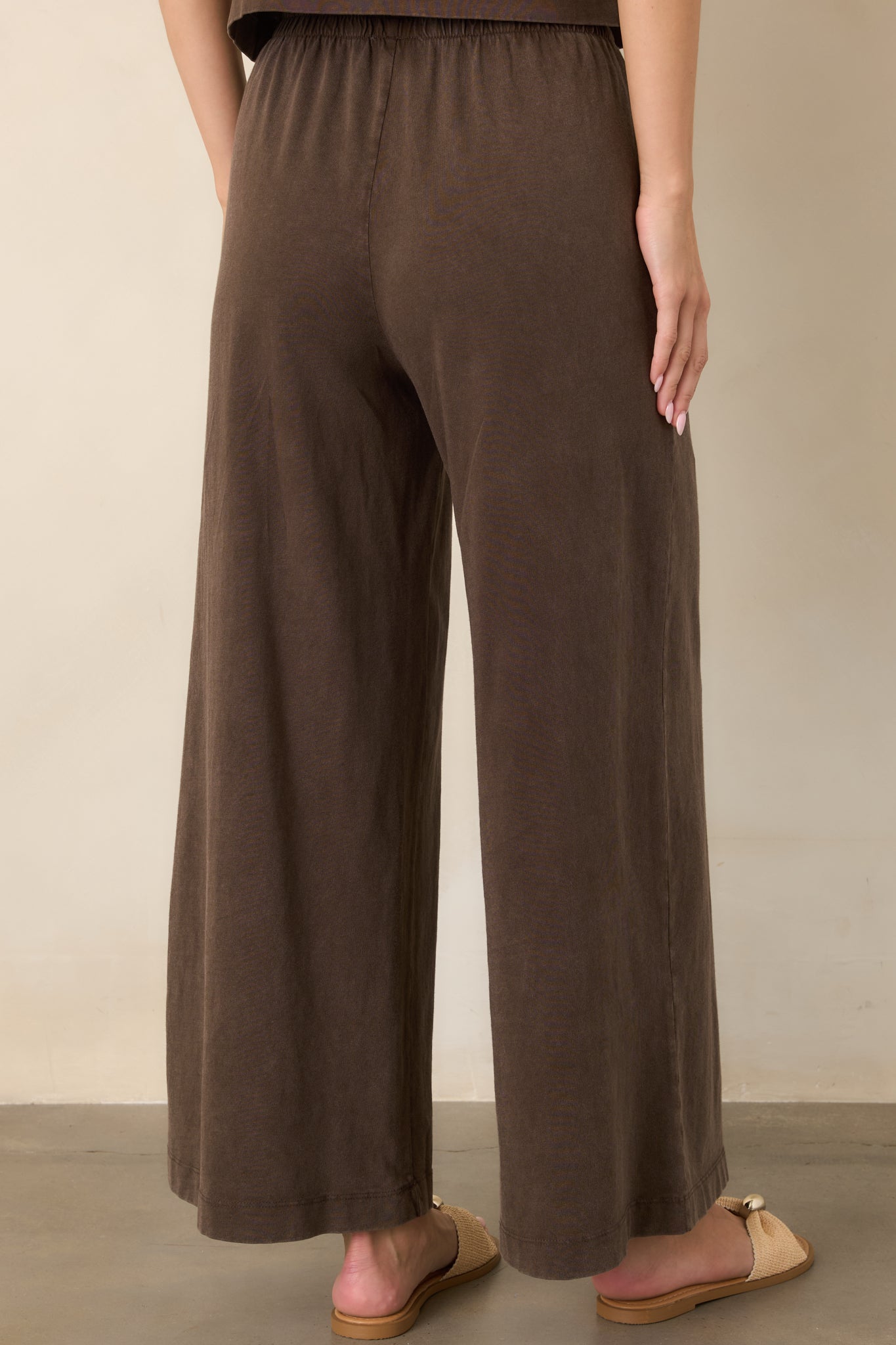 Rear view of the dark chocolate brown pants showing the relaxed fit, elastic waistband, and wide-leg silhouette.
