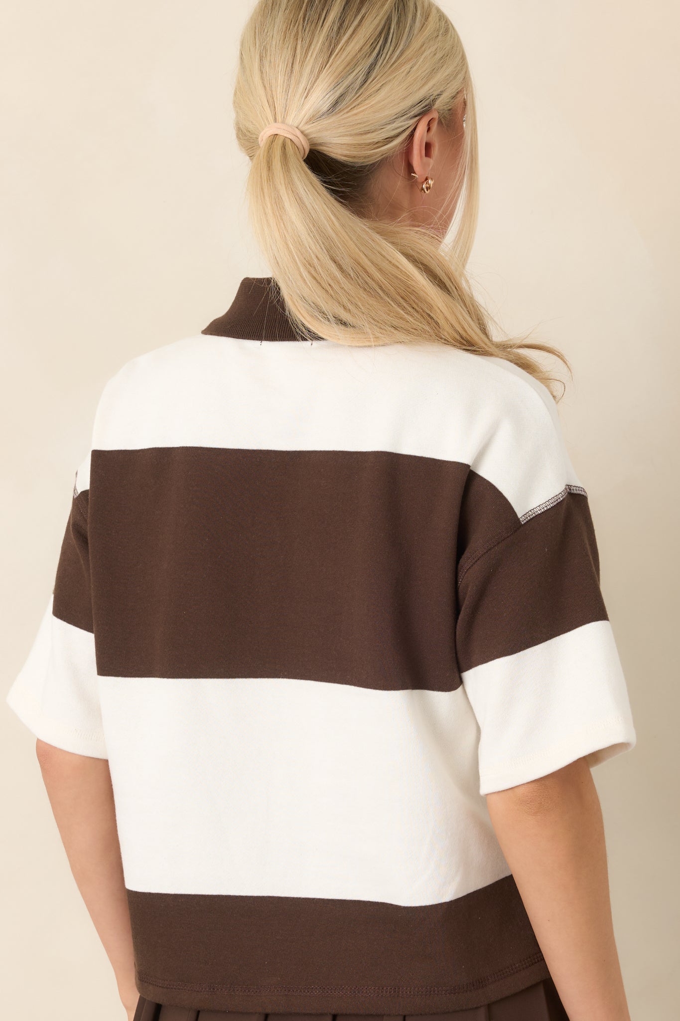Rear view of the dark chocolate and ivory colorblock top showing its relaxed boxy fit, dropped shoulders, short sleeves, and cropped hem.