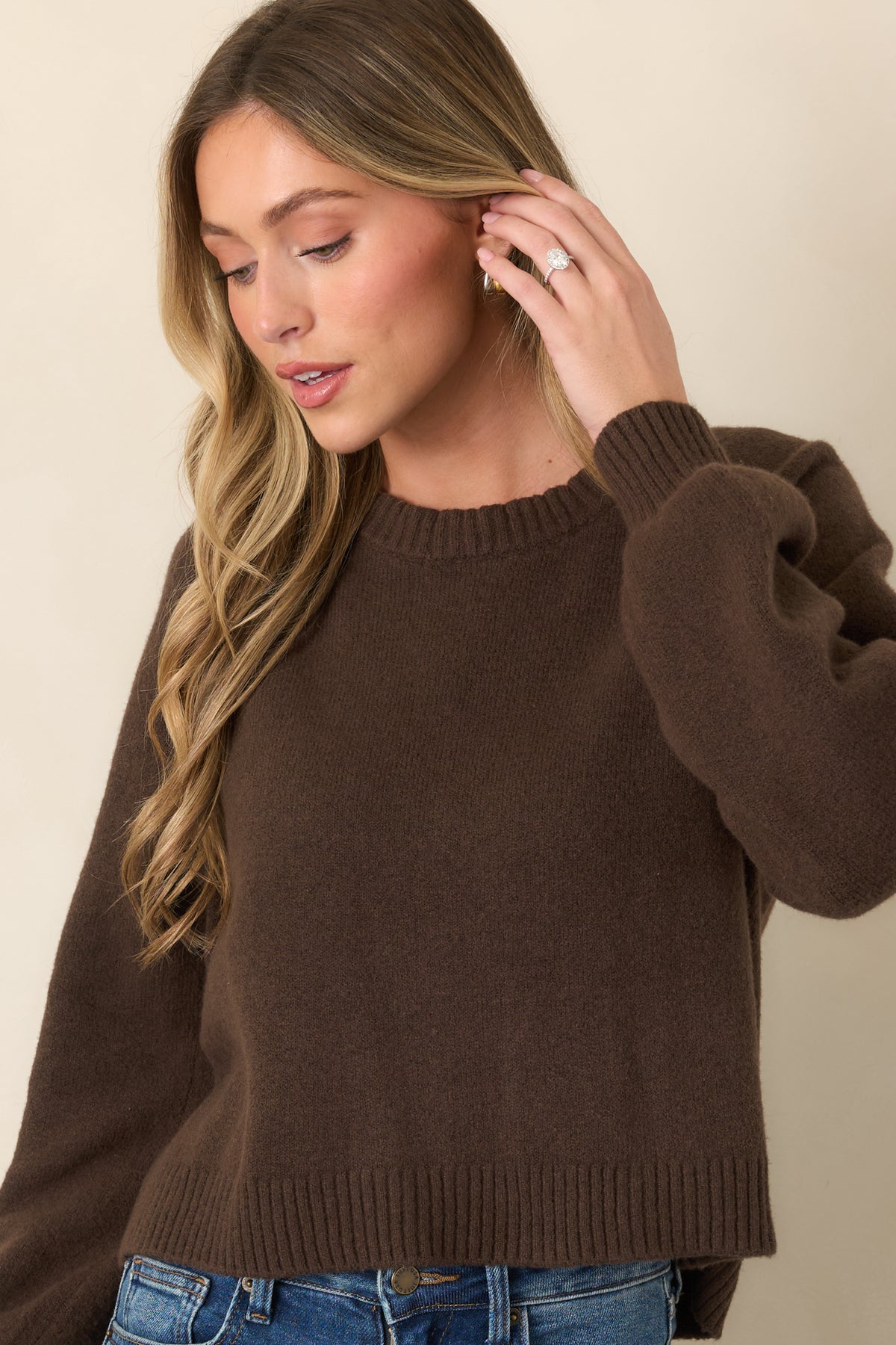 Dark chocolate sweater highlighting the ribbed cuff and smooth knit texture across the relaxed sleeve construction.
