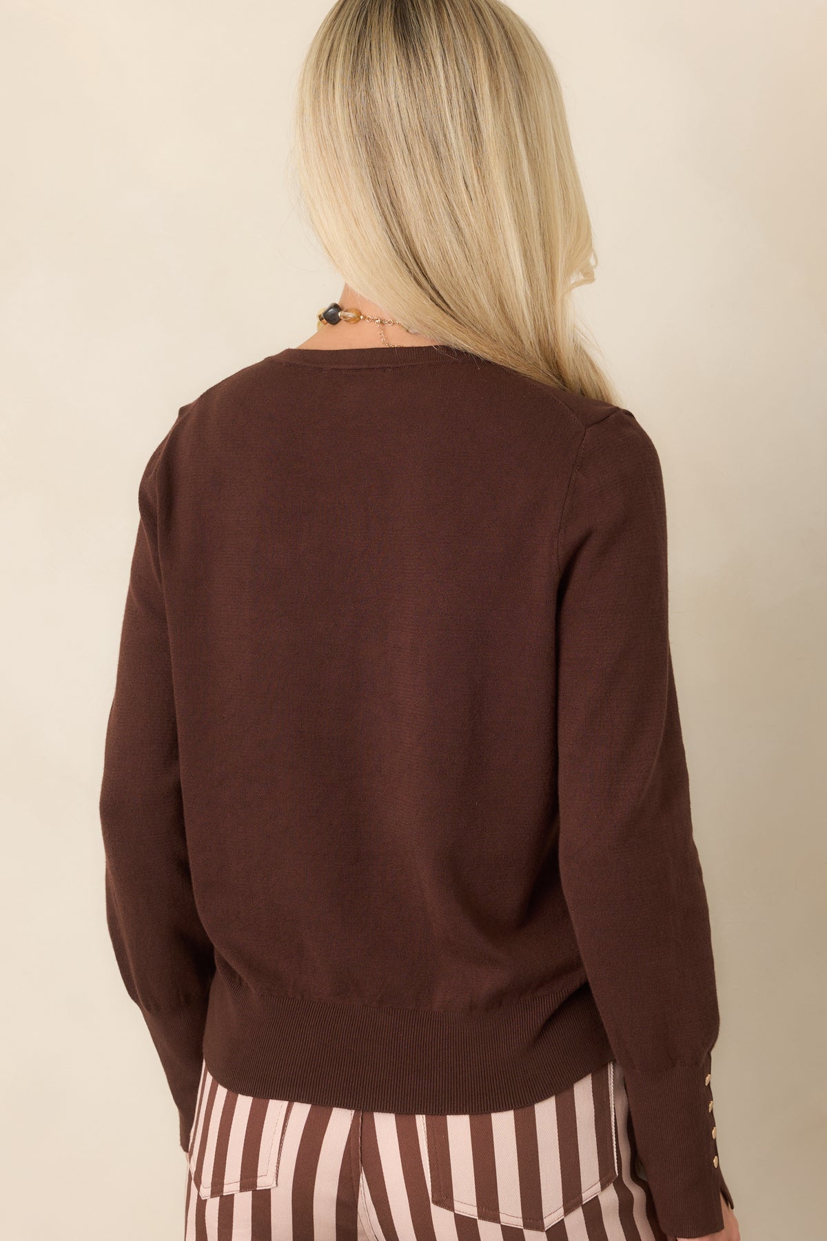 Rear view of the dark chocolate long-sleeve top, highlighting its straight silhouette, crew neckline, ribbed hem, and elongated cuffs.